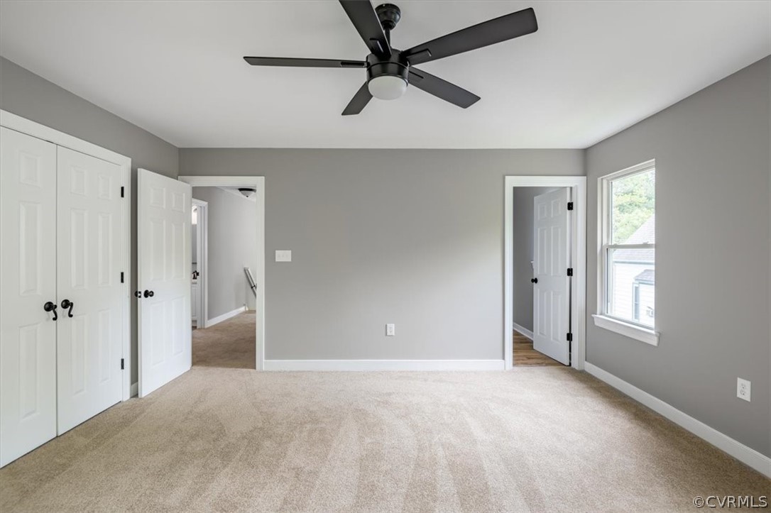 Unfurnished bedroom with light colored carpet and ceiling fan