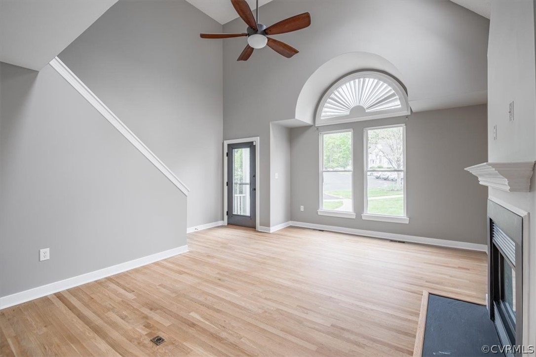 Unfurnished living room featuring high vaulted ceiling, light hardwood / wood-style flooring, and ceiling fan