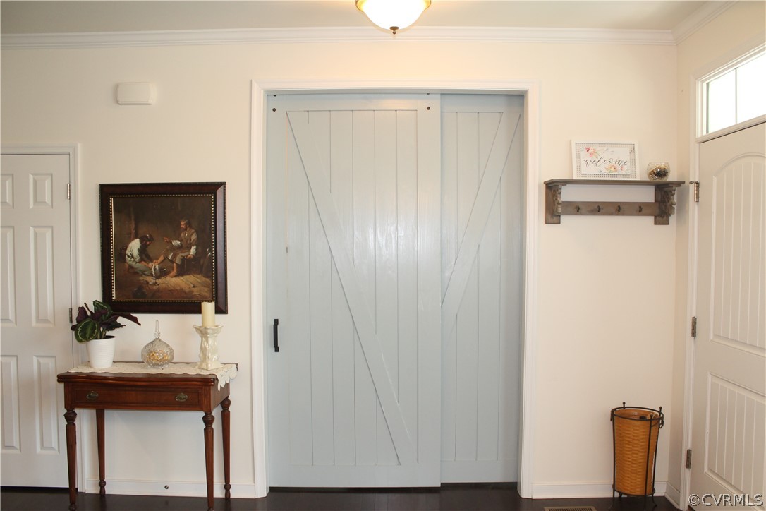 Doorway with dark hardwood / wood-style flooring and crown molding