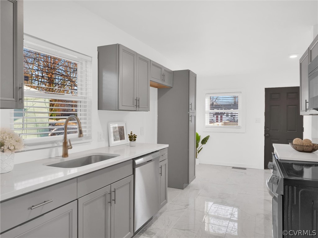 Kitchen with electric range oven, sink, light tile flooring, gray cabinetry, and stainless steel dishwasher