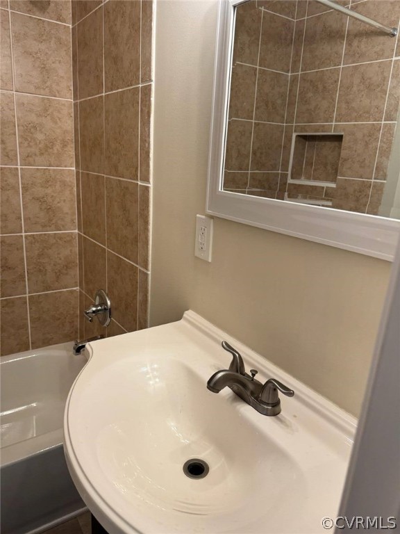 Bathroom featuring tiled shower / bath combo and sink