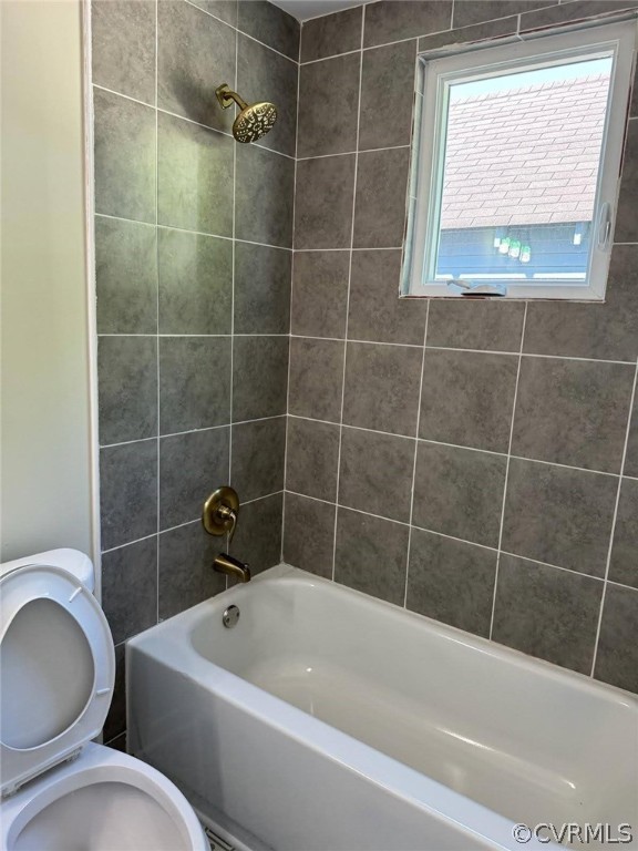 Bathroom with toilet and tiled shower / bath combo
