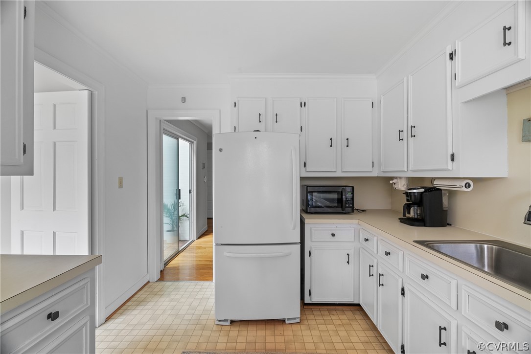 Kitchen with white fridge, light tile floors, and white cabinets