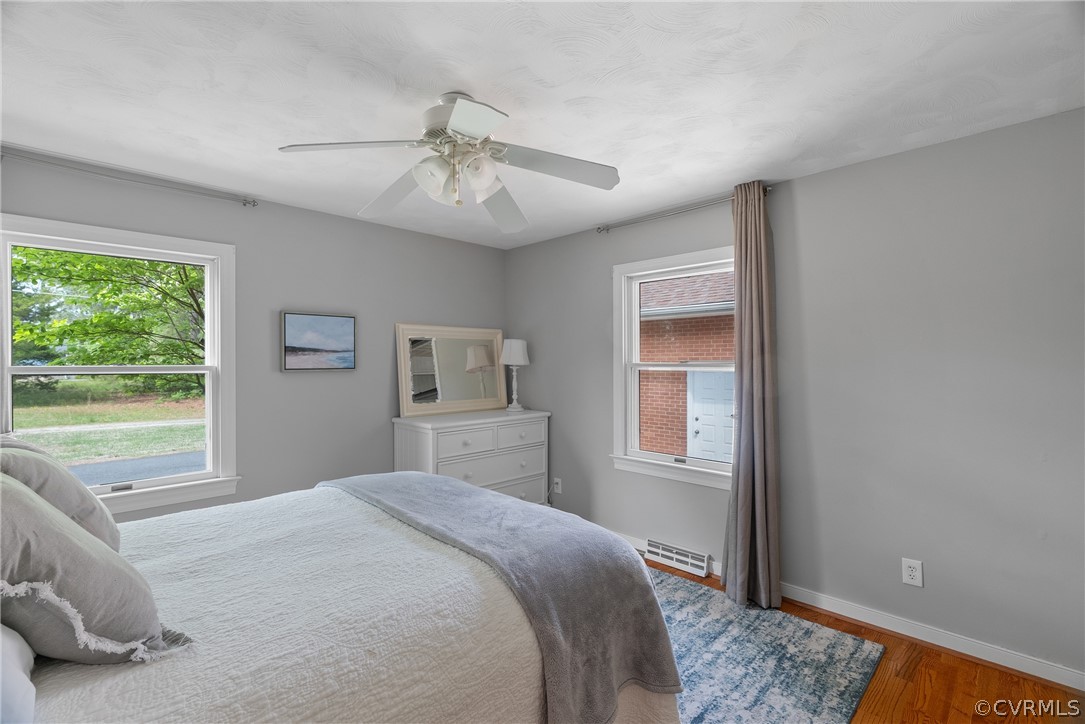 Bedroom featuring wood-type flooring, ceiling fan, and baseboard heating