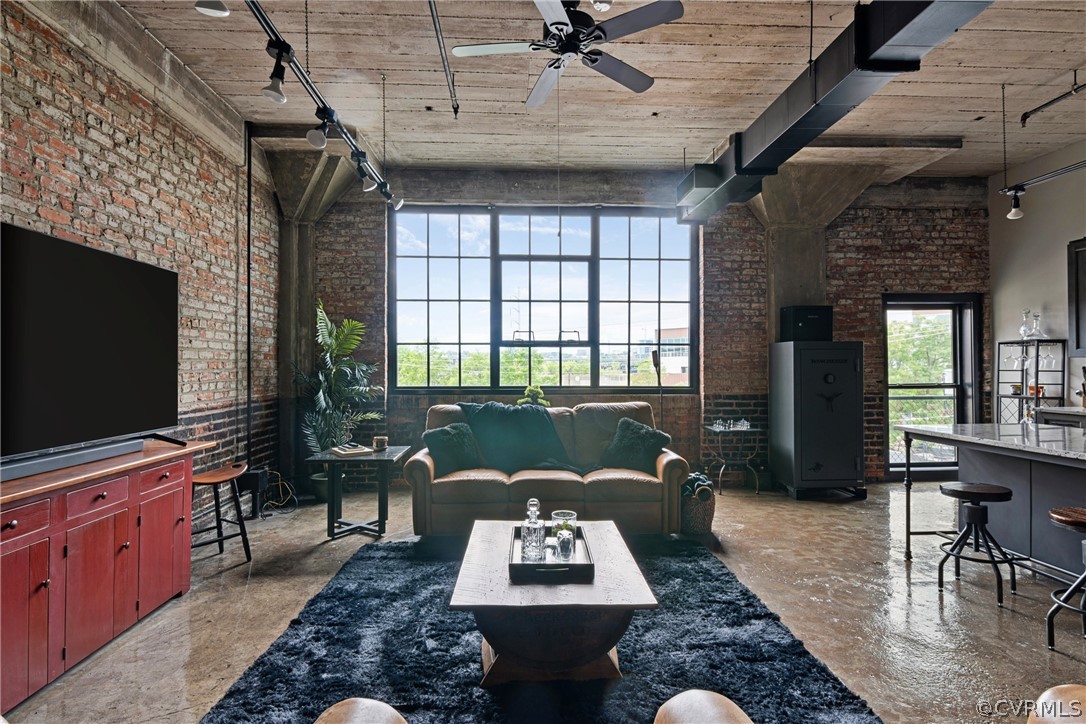 Living room featuring  exposed bricks, newly refinished concrete flooring, ceiling fan, and track lighting. NEW WINDOWS