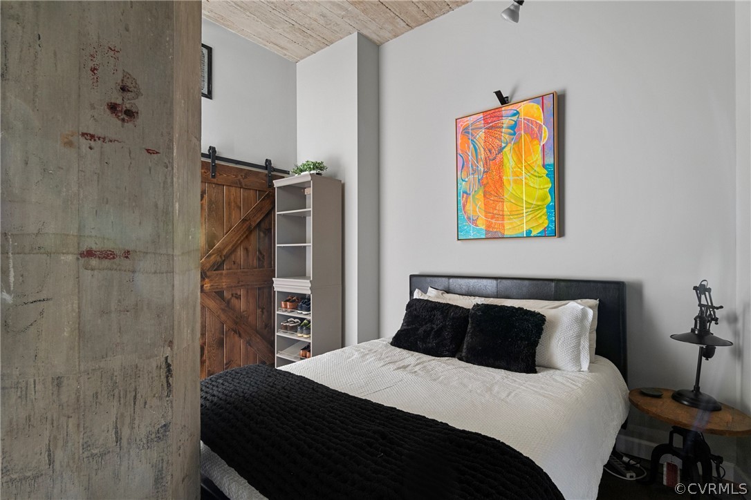 Bedroom with a barn door and wooden ceiling