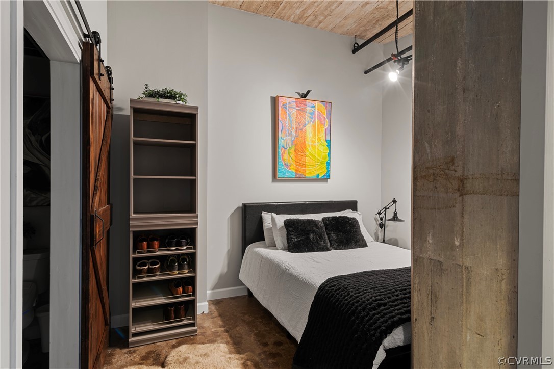 Bedroom featuring wood ceiling, concrete floors, and a barn door