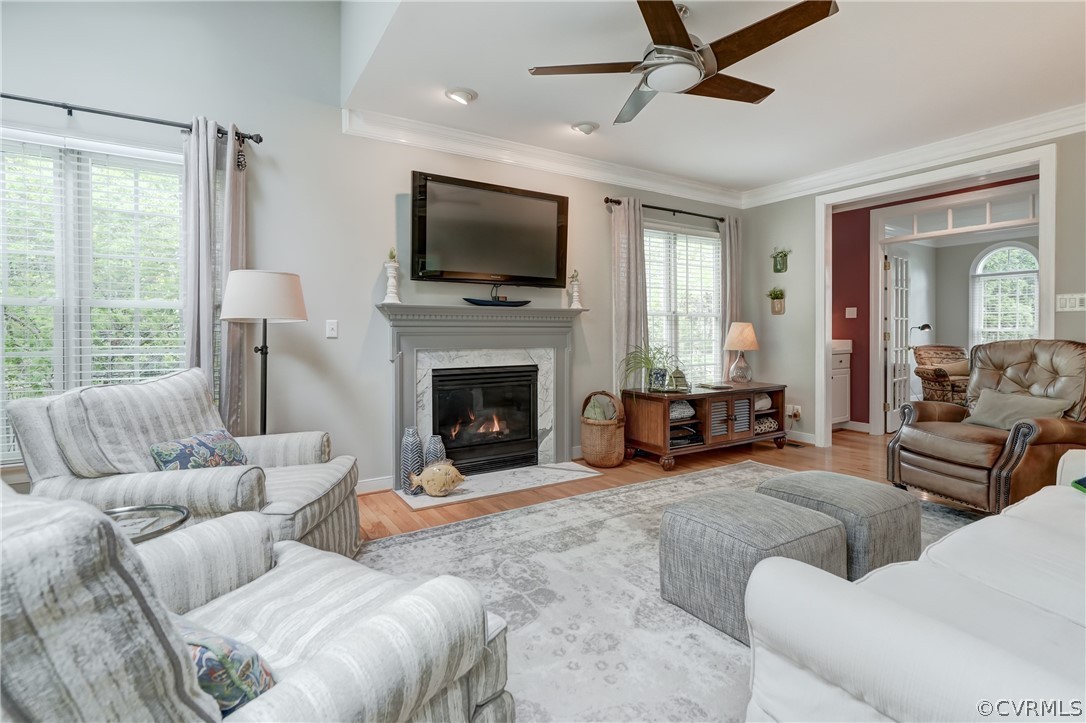 Family room with Gas Heatolator  Fireplace wood flooring, plenty of natural light, and ceiling fan