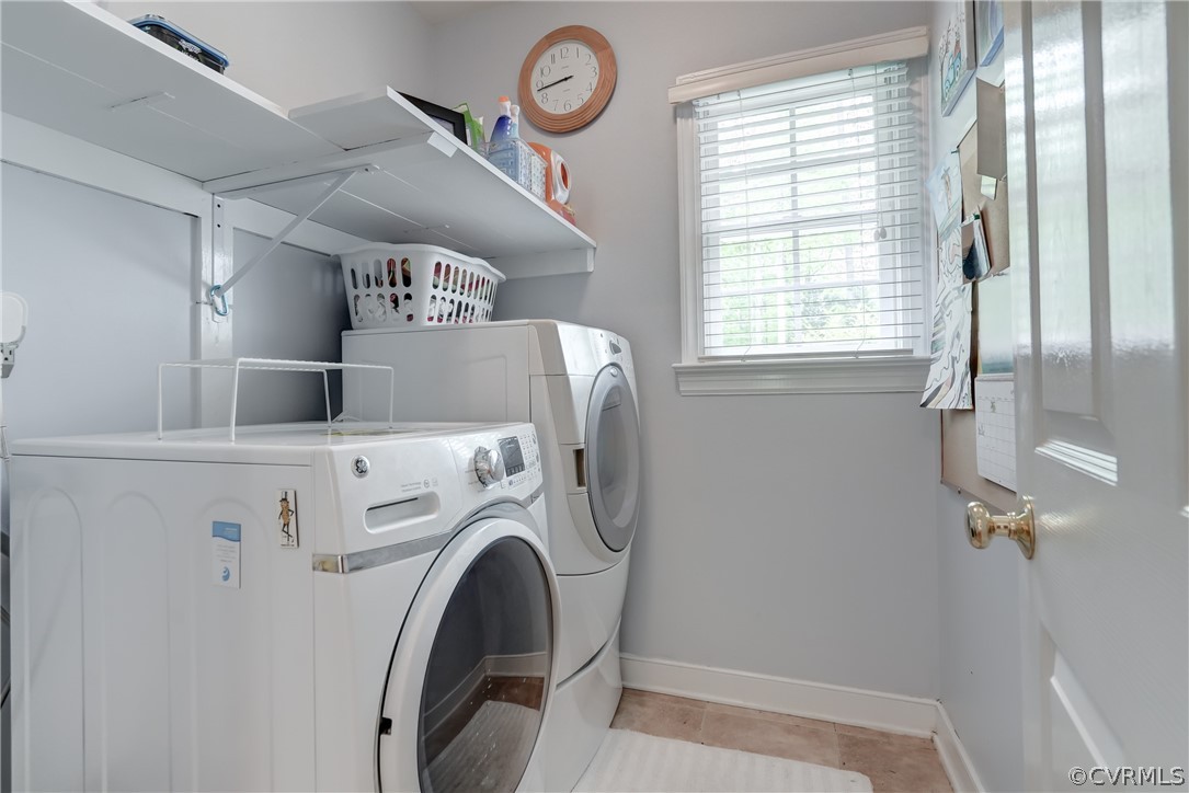 Laundry room with washing machine and dryer and light tile floors