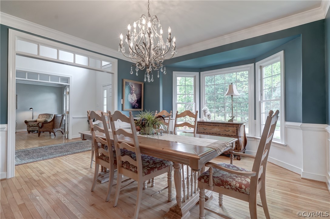 Dining room featuring light hardwood  flooring, crown molding, and a chandelier