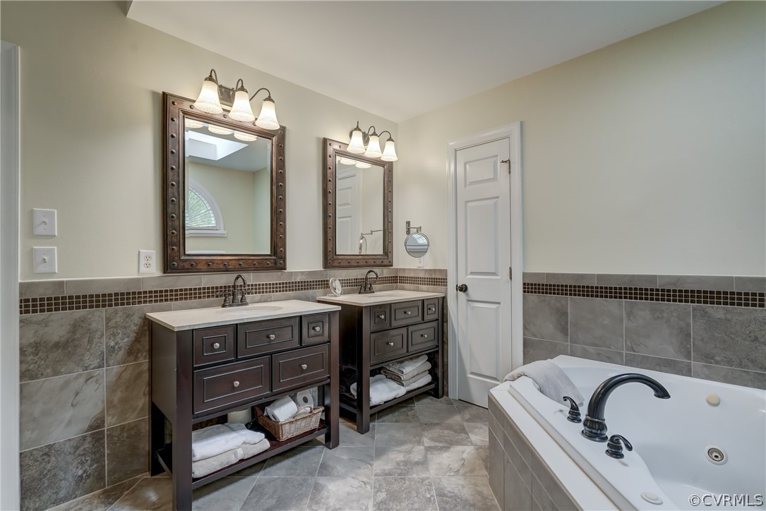 Primary Bathroom featuring tile flooring, tile walls, backsplash, and dual vanity