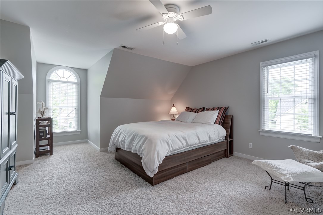 Carpeted bedroom featuring ceiling fan and vaulted ceiling
