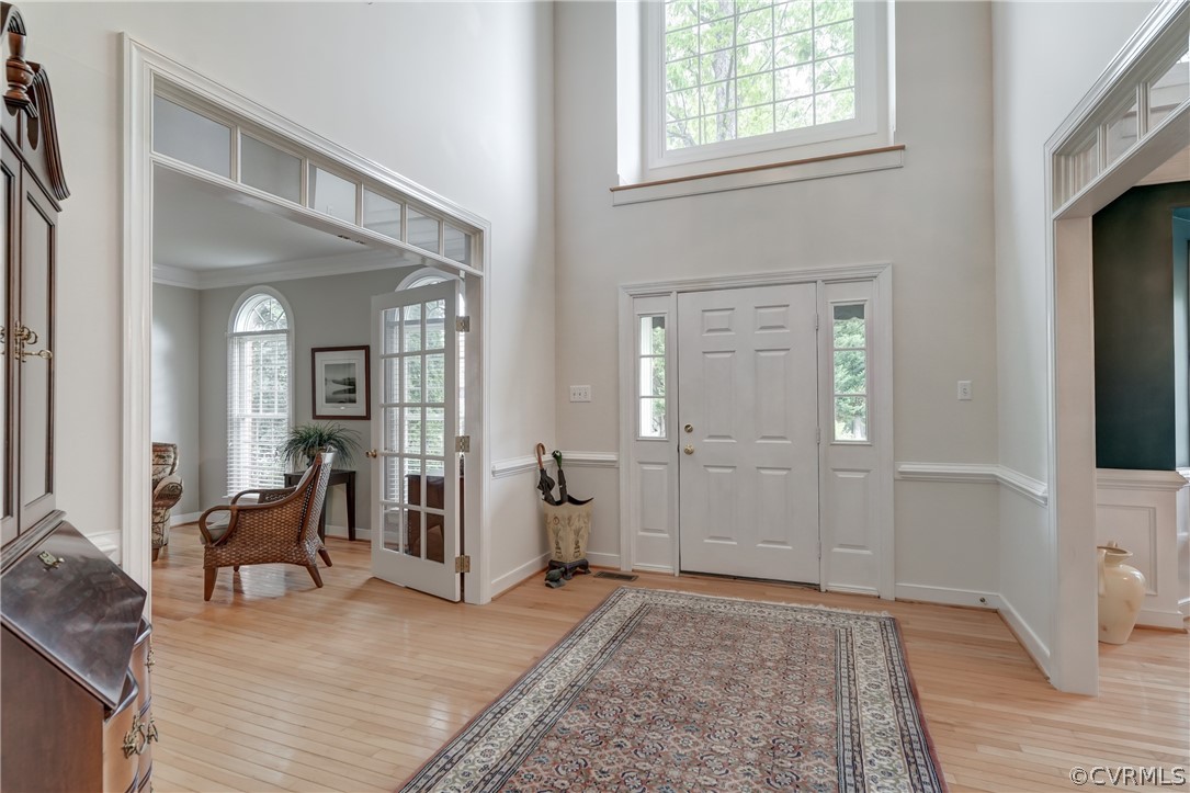 Entrance foyer featuring hardwood  floors, a wealth of natural light, a towering ceiling, and crown molding