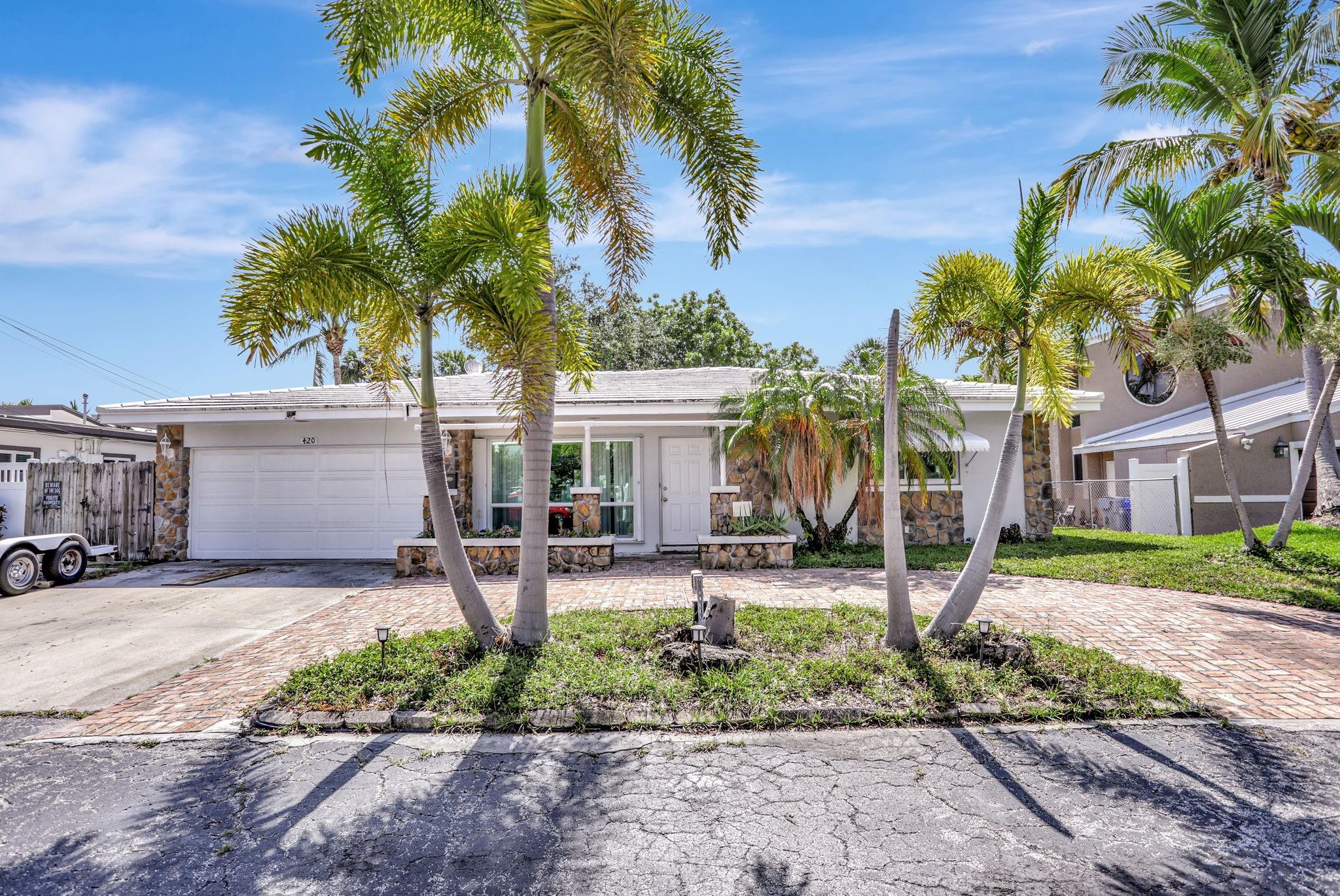 Do not miss this charming waterfront home! Fantastic location near Atlantic and Federal offers shopping, dining, and services very nearby. Only 1.5 miles to the sandy beach! Snug Harbor neighborhood has great neighbors in a waterfront community with a laid-back coastal vibe. Fully renovated homes in this neighborhood are valued around $1.4MM. Situated on a 100' wide canal for privacy, 70' of water frontage and a 50' dock. Fixed bridge has 12' clearance. This home boasts impact windows, a spacious floor plan, fireplace, original terrazzo floors, central AC, laundry, and a two-car garage. Plenty of room for a pool! Enjoy a day out on the water and return to shady afternoons in the backyard under a mature tree canopy. This is Florida living at its best—peaceful, sunny and full of possibility!
