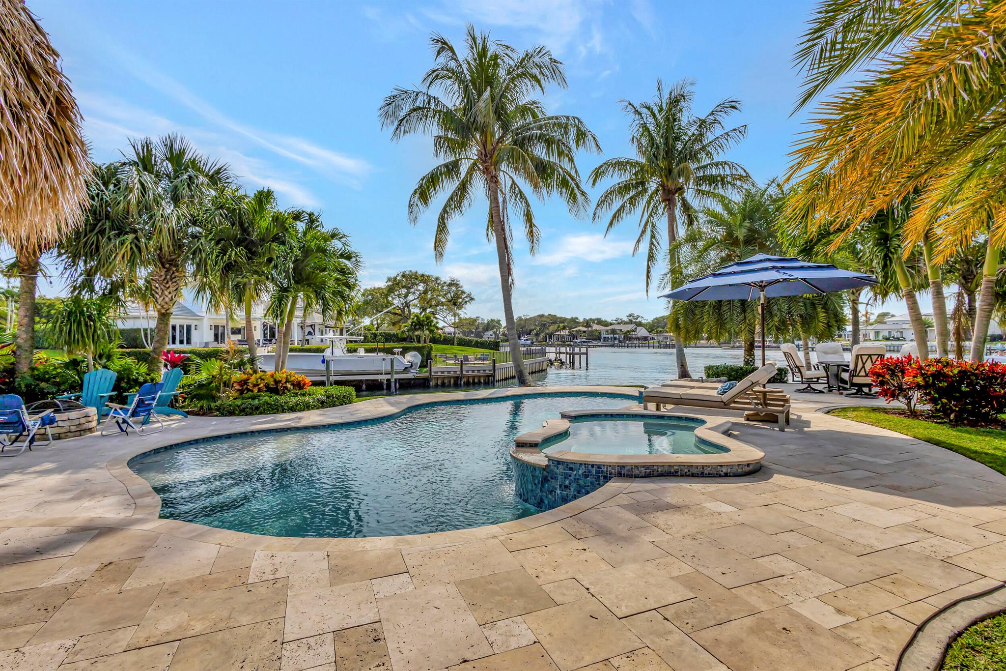 Welcome to your dream home! This rare intracoastal point property boasts unparalleled luxury and stunning waterfront views. Built in 2018, this 4-bedroom, 4-bathroom pool home offers the ultimate in waterfront living. With over 300 ft of water frontage and over 700 ft line of site across the intracoastal, this home features a deep water dock with no fixed bridges in a no wake zone, one private boat lift on a 60 ft. dock, and two jet ski lifts. Over 2,000 sq. ft of outdoor deck and walkways, you'll enjoy endless entertaining with your tiki and full outdoor kitchen. Inside, two primary bedrooms (one upstairs & one downstairs) offer privacy and comfort. The upstairs primary bedroom includes a separate living area and a big outdoor balcony where you can enjoy spectacular sunset views.. Modern finishes in the bathrooms and kitchen with high-end appliances. Porcelain tile throughout the living area with carpet in the bedrooms. Two additional bedrooms and a den/office downstairs complete this exquisite home, offering the ultimate waterfront lifestyle.