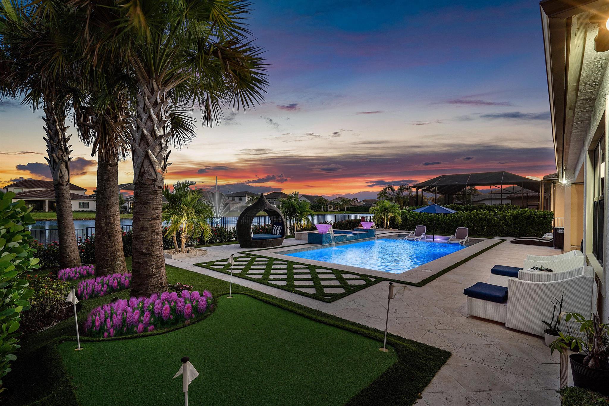 Luxurious Lakefront Living in Sonoma Isles Jupiter. Welcome to a breathtaking ''Garden Vista'' model home situated in the prestigious gated community of Sonoma Isles in Jupiter. This exquisite residence, built in 2021, offers 4,287 square feet of thoughtfully designed living space, featuring 5 bedrooms, 4.1 bathrooms, a private office, a spacious loft, and a stunning all-glass wine room--all nestled on a serene fountain lakefront lot. Step through the grand double-impact decorative glass entry doors into a home where modern elegance meets resort-inspired comfort. The soaring ceilings and custom designer spiral staircase, accentuated with wrought-iron railings, create a captivating first impression. The heart of the home is a chef's dream kitchen with upgraded and expansive quartz counterto custom cabinetry, a designer marble backsplash, and a spacious island that flows into the open-concept living areas. Top-of-the-line appliances, a gas range with a stunning pot filler, butler's pantry and a custom fitted walk-in pantry make cooking and entertaining effortless. Adjacent to the kitchen, the formal dining area boasts custom backlit glass wine room, perfect for showcasing your wine or favorite champagne collections. The luxurious primary suite is a private retreat with a sitting area overlooking the resort-style pool and lake. The suite features a stunning white stacked marble accent wall with a built-in fireplace and niche for TV. Enjoy the spa-like bathroom with an ultra-large walk-in shower and dual walk-in closets complete with custom California Closet systems and a 3-way mirror. Designer window treatments, crown-molding, trim work, custom California closets, and sophisticated finishes shine throughout the home. Step outside to a backyard that rivals the finest resorts. The saltwater, gas-heated pool and raised spa feature a sun-shelf for lounging, waterfalls, and dazzling glass water bowls with color-changing lighting effects. Professional landscaping enhances the lush, private ambiance, while the tongue-and-groove lanai ceiling creates an inviting space for alfresco dining. A custom putting green adds to the fun, and the expansive lake and fountain views provide the perfect backdrop for sunrise and sunset moments. This home is designed for ease and functionality, with a spacious three-car garage featuring epoxy floors for durability and style. The garage is equipped with custom cabinetry and a work center, offering ample storage and organization for any project or hobby. Sonoma Isles offers a wealth of community amenities, including a state-of-the-art clubhouse, fitness center, community pool, spa, scenic walking trails, tennis and pickleball courts, a playground, and a cozy fire pit for sunset views. Conveniently located near championship golf courses, upscale shopping, top-rated schools, this home ensures every convenience is within easy reach. Don't miss the opportunity to make this exceptional property your home. Schedule your private tour today and experience the unparalleled lifestyle of Sonoma Isles!