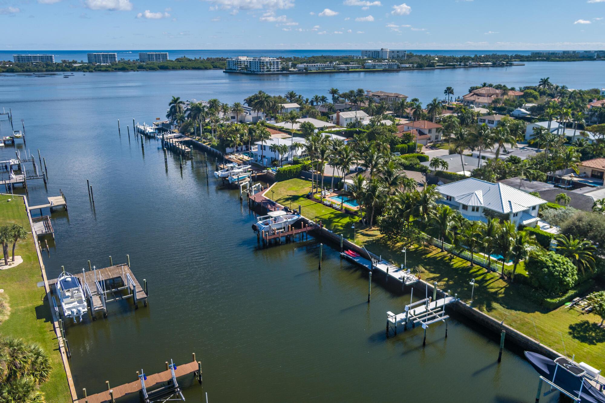 This stunning waterfront property in Lake Worth offers the perfect blend of luxury, privacy, and functionality. Situated at the end of a quiet cul-de-sac, the home boasts 125 feet of water frontage with a private dock, a 13,000-pound boat lift, and serene views from almost every room. Designed for both relaxation and entertaining, the property features a beautifully landscaped yard, a heated saltwater pool, and a covered outdoor loggia. Inside, the light and bright interior spans 4,546 square feet and is thoughtfully designed with seamless indoor-outdoor living in mind. The two-story foyer creates a grand first impression, leading to elegant living and dining rooms that open directly to the pool and waterfront. A large family room with a wet bar connects to the gourmet kitchen, which is perfect for the culinary enthusiast. The kitchen boasts a gas range, Sub-Zero refrigerator, a full Viking wine fridge, a cooled wine closet, and a walk-in pantry/laundry room. Upstairs, the primary suite is a luxurious retreat featuring two walk-in closets, dual sinks, a soaking tub, a large shower, and a private water closet, all complemented by stunning water views. Two additional upstairs guest suites each include en suite baths and spacious closets. A fourth bedroom, located on the main floor, provides flexibility and convenience. Built for peace of mind, the home is equipped with hurricane impact doors and windows, a thick gauge standing-seam metal roof with straps, and a 24 kW generator. A whole-house water filtration system ensures fresh water throughout, while a security and camera system enhances safety. Full landscape lighting adds to the property's charm, while a two-car garage and extended driveway offer ample parking.