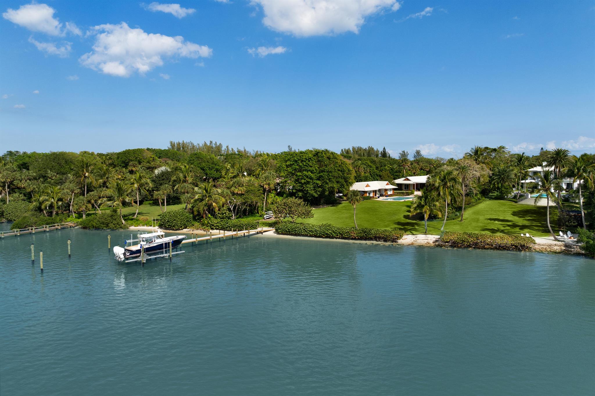 A rare ocean-to-intracoastal estate on Jupiter Island's exclusive Gold Coast. This meticulously renovated property spans nearly 4 acres and includes a main house with 3BR + den/office, 3.5 car garage, and 2BR guest house. Enjoy 133' of private beach, 137' of Intracoastal frontage with a new 45' Weardeck dock & preserve views. The main house offers a split floor plan with ensuite bedrooms, a custom Rick Baker London kitchen, spacious living areas with water views, and an expansive backyard with a heated saltwater pool & Coquina decking. Enjoy a USGA designed 2-hole golf course, lush tropical landscaping, and a long tree-lined driveway for ultimate privacy. 318 S Beach is an extraordinary estate offering unmatched luxury, privacy, and stunning views - ideal for a true coastal lifestyle!