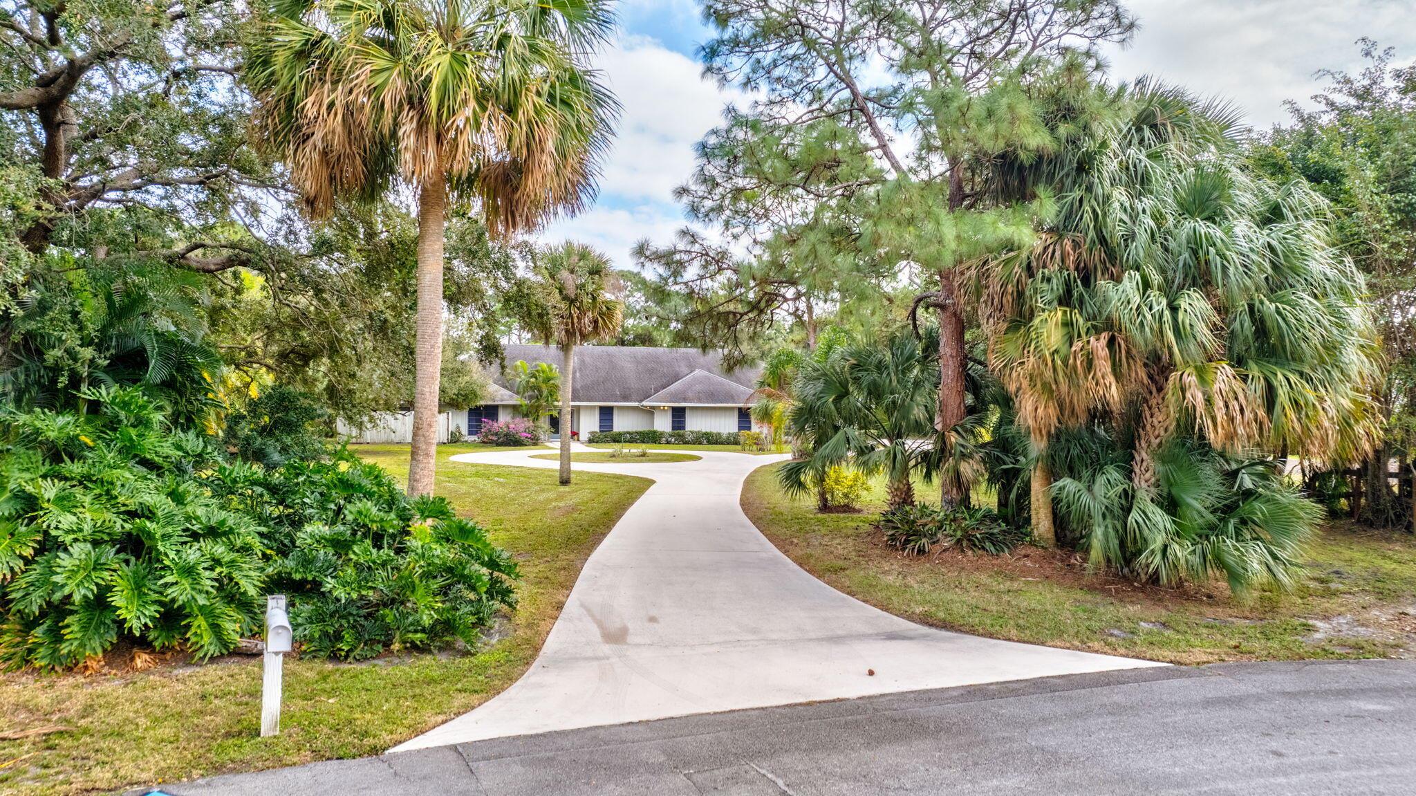 Privacy awaits on nearly 1.5 acres bordered by canal and tucked away towards a quiet end of the community, offering in-town, ranch living in gated Horseshoe Acres! Architecturally unique to bring your finishing touches and thoughtfully laid out over approximately 2,965 square feet of one-level living space. Beyond the entry, voluminous ceilings await, as you entertain in the formal living room with custom built-ins and coral fireplace, and elevated dining room area, overlooking the lushly landscaped backyard beyond. The updated kitchen features white shaker cabinetry, Corian counters, stainless-steel appliances, walk-in pantry, eat-in area, and opens to the adjacent den with custom built-in cabinetry. Retreat to the Primary suite with custom built-ins and Primary bath with privacy garden, dual sinks, separate shower, Roman soaking tub, and expansive, walk-in closet, with custom built-in. Guest accommodations across the split-floor plan of the main house, feature two additional bedrooms that share a full bath, and a fourth bedroom with en-suite bath adjacent to the Primary. Relax on the covered, screened-in patio overlooking the substantial park-like grounds and canal, with plenty of room for a pool. Spacious, concrete circular drive leads to an oversized 3-car garage with half bath, and abundant extra storage. 

Enjoy all that equestrian-friendly Horseshoe Acres has to offer: 24/7 gate, close proximity to dining, shopping, beaches, education, I-95 &amp; Turnpike, the Palm Beach International Airport, and more!