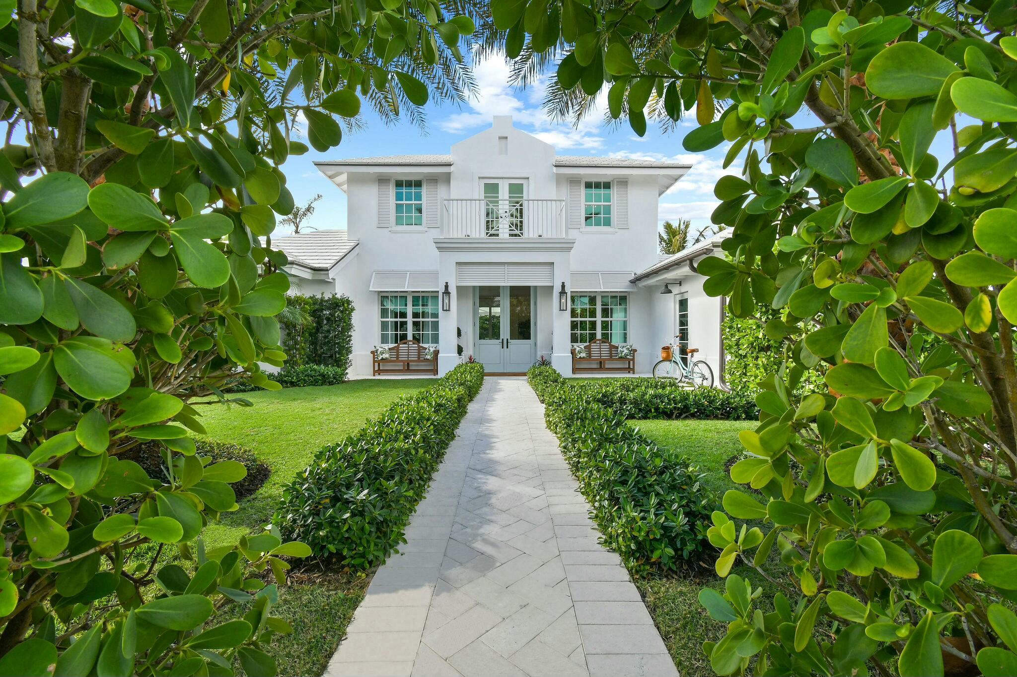 Step into a rare opportunity to own one of the most remarkable interior homes in Jupiter Inlet Colony--a luxurious sanctuary that seamlessly combines high-end design with timeless coastal charm. Situated on one of the highest elevations in the Colony, this home underwent a complete transformation in late 2021, resulting in a masterpiece of refined elegance. The white exterior, inspired by Cape Dutch architecture, is adorned with Bevolo gas lanterns, towering Sylvester palms, lush Bermuda grass, and meticulously maintained Clusia hedges, creating an inviting yet private oasis in this sought-after beachside community. Every element, from the custom Chippendale stairwell to the exquisite Urban Electric and Palecek lighting, has been thoughtfully curated to offer a one-of-a-kind coastal living experience. The interior features expansive, light-filled living spaces enhanced by nickel joint shiplap, coffered ceilings, a whitewashed Pecky Cypress fireplace, and wide plank white oak flooring. At the heart of the home is a stunning gourmet kitchen, anchored by a Lacanche range and a Calacatta Gold marble island, ideal for both entertaining and daily living. A built-in bar area, marble backsplash, inset cabinetry, and dual dishwashers complete the kitchen's flawless design. The dining room flows effortlessly into the spacious living and family rooms, providing a perfect setting for hosting gatherings or enjoying quiet family moments. The main floor boasts luxurious primary and guest suites, each featuring beautifully appointed bathrooms and walk-in closets. Upstairs, two oversized ensuite bedrooms and a cozy sitting area lead to a balcony overlooking the property's lush front yard, offering a serene escape.
The exterior is a private haven, enclosed by a stucco wall and 10-foot hedges. The manicured backyard features an idyllic turf lawn, a gunite pool, a custom 30-foot retractable awning, an outdoor shower, and even a putting green&#x14;all accessible through floor-to-ceiling glass doors. This home is truly move-in ready, blending modern conveniences with timeless sophistication. Nestled on the southern tip of Jupiter Island, Jupiter Inlet Colony is a picturesque enclave in Palm Beach County, offering unmatched serenity and exclusivity. This charming community spans less than 0.2 square miles and is bordered by the Atlantic Ocean, the Intracoastal Waterway, and the Jupiter Inlet. With pristine beaches, world-class boating, fishing, and water sports, it's an idyllic setting for coastal living. Safety and peace of mind are paramount, with the town's dedicated police department ensuring a secure environment.
If you're searching for a home that combines elegance, style, and an unbeatable location in one of Florida's most coveted neighborhoods, look no further&#x14;this extraordinary property is the perfect choice.