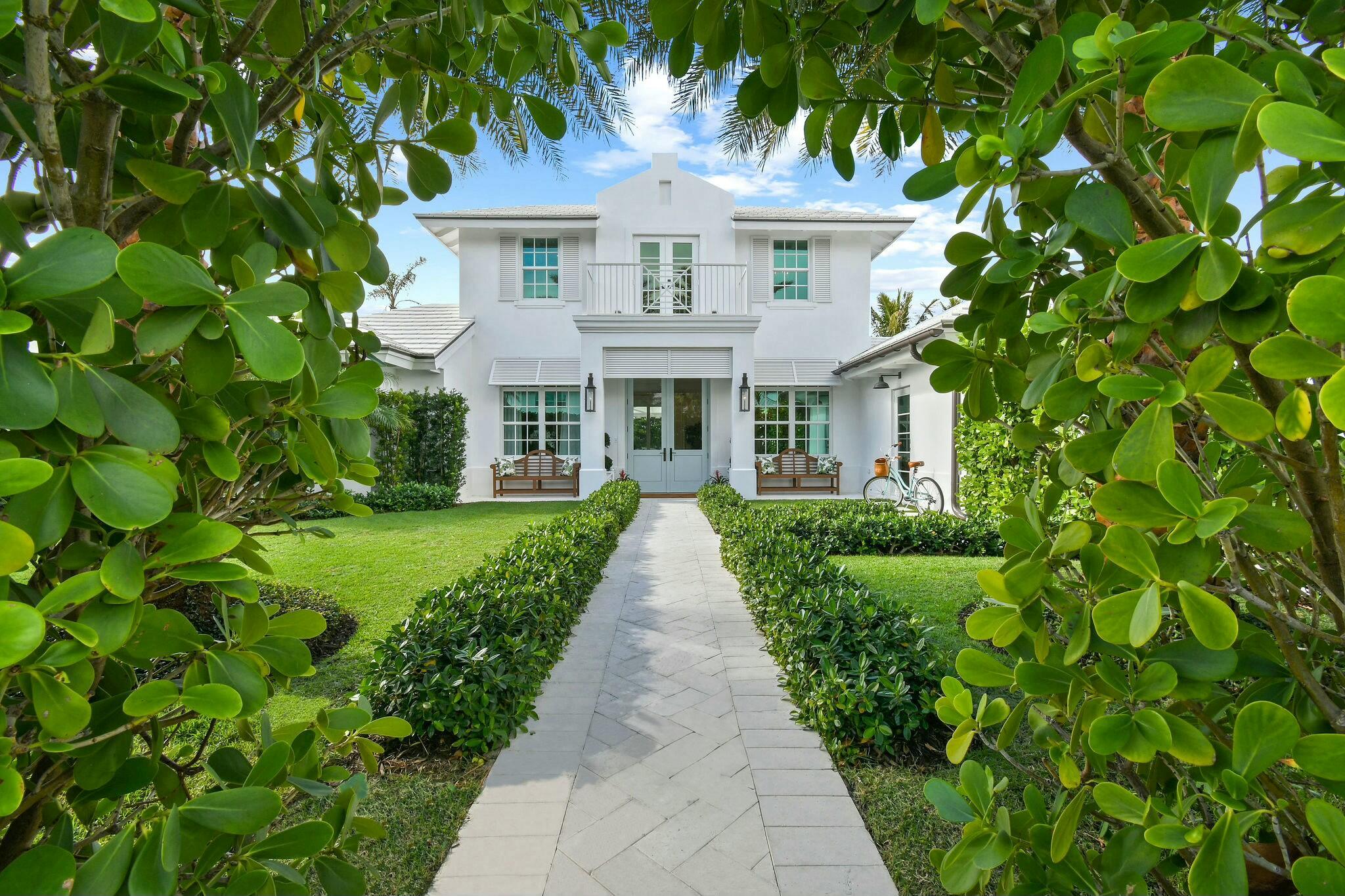 Step into a rare opportunity to own one of the most remarkable interior homes in Jupiter Inlet Colony--a luxurious sanctuary that seamlessly combines high-end design with timeless coastal charm. This home underwent a complete transformation in late 2021, resulting in a masterpiece of refined elegance. The white exterior, inspired by Cape Dutch architecture, is adorned with Bevolo gas lanterns, towering Sylvester palms, lush Bermuda grass, and meticulously maintained Clusia hedges, creating an inviting yet private oasis in this sought-after beachside community. Every element, from the custom Chippendale stairwell to the exquisite Urban Electric and Palecek lighting, has been thoughtfully curated to offer a one-of-a-kind coastal living experience. The interior features expansive, light-filled living spaces enhanced by nickel joint shiplap, coffered ceilings, a whitewashed Pecky Cypress fireplace, and wide plank white oak flooring. At the heart of the home is a stunning gourmet kitchen, anchored by a Lacanche range and a Calacatta Gold marble island, ideal for both entertaining and daily living. A built-in bar area, marble backsplash, inset cabinetry, and dual dishwashers complete the kitchen's flawless design. The dining room flows effortlessly into the spacious living and family rooms, providing a perfect setting for hosting gatherings or enjoying quiet family moments. The main floor boasts luxurious primary and guest suites, each featuring beautifully appointed bathrooms and walk-in closets. Upstairs, two oversized ensuite bedrooms and a cozy sitting area lead to a balcony overlooking the property's lush front yard, offering a serene escape.
The exterior is a private haven, enclosed by a stucco wall and 10-foot hedges. The manicured backyard features an idyllic turf lawn, a gunite pool, a custom 30-foot retractable awning, an outdoor shower, and even a putting green&#x14;all accessible through floor-to-ceiling glass doors. This home is truly move-in ready, blending modern conveniences with timeless sophistication. Nestled on the southern tip of Jupiter Island, Jupiter Inlet Colony is a picturesque enclave in Palm Beach County, offering unmatched serenity and exclusivity. This charming community spans less than 0.2 square miles and is bordered by the Atlantic Ocean, the Intracoastal Waterway, and the Jupiter Inlet. With pristine beaches, world-class boating, fishing, and water sports, it's an idyllic setting for coastal living. Safety and peace of mind are paramount, with the town's dedicated police department ensuring a secure environment.
If you're searching for a home that combines elegance, style, and an unbeatable location in one of Florida's most coveted neighborhoods, look no further&#x14;this extraordinary property is the perfect choice.