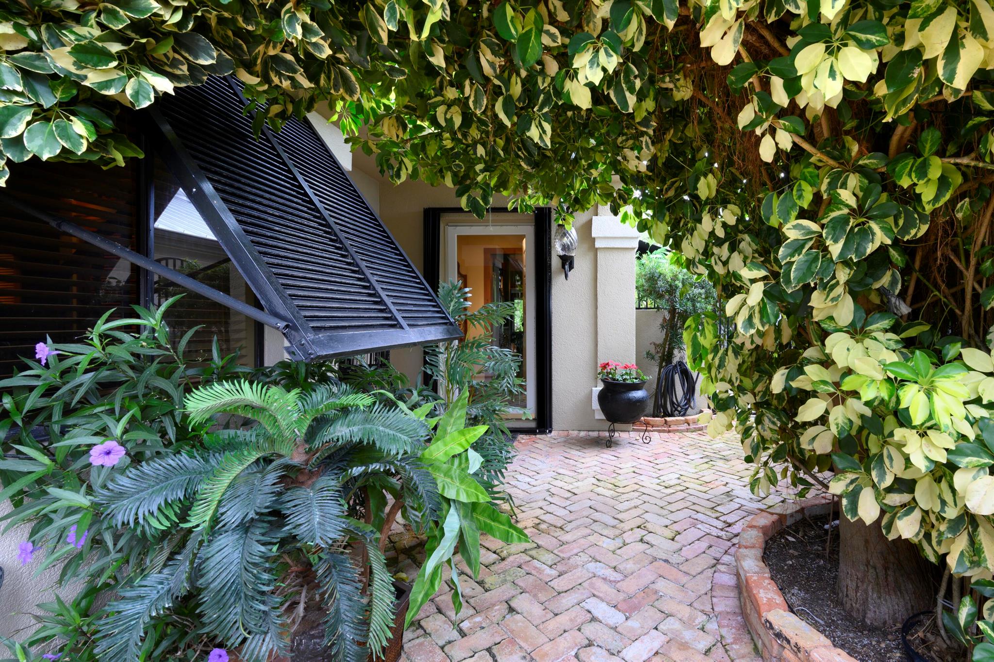 This charming 3-bedroom, 2-bathroom home features a 2-car garage and is surrounded by lush, tropical landscaping both in the front and back. Enjoy the elegance of a Chicago Brick driveway and the durability of a metal roof. Inside, you'll find beautiful laminate floors throughout the living areas and stylish tile in the bathrooms. The kitchen is equipped with modern stainless-steel appliances and sleek stainless steel countertops. The spacious primary bedroom boasts an ensuite bath for ultimate privacy and comfort and extra closet space.  Two additional bedrooms, one with a loft, offer flexibility and ample space. The open dining area seamlessly flows into the cozy breakfast nook, perfect for casual meals. For extra living space, step into the large, enclosed Florida room, ideal for relaxation or entertainment. Outside, the patio invites you to enjoy the outdoors in style. Beach access just steps away, offering the perfect coastal retreat.
Amenities include, tennis, pool, pickleball, basketball, sidewalks, picnic area and club house. Minutes to the beaches, boating and recreation. Close to dining and entertainment. Easy access to major highways and Palm Beach International Airport.