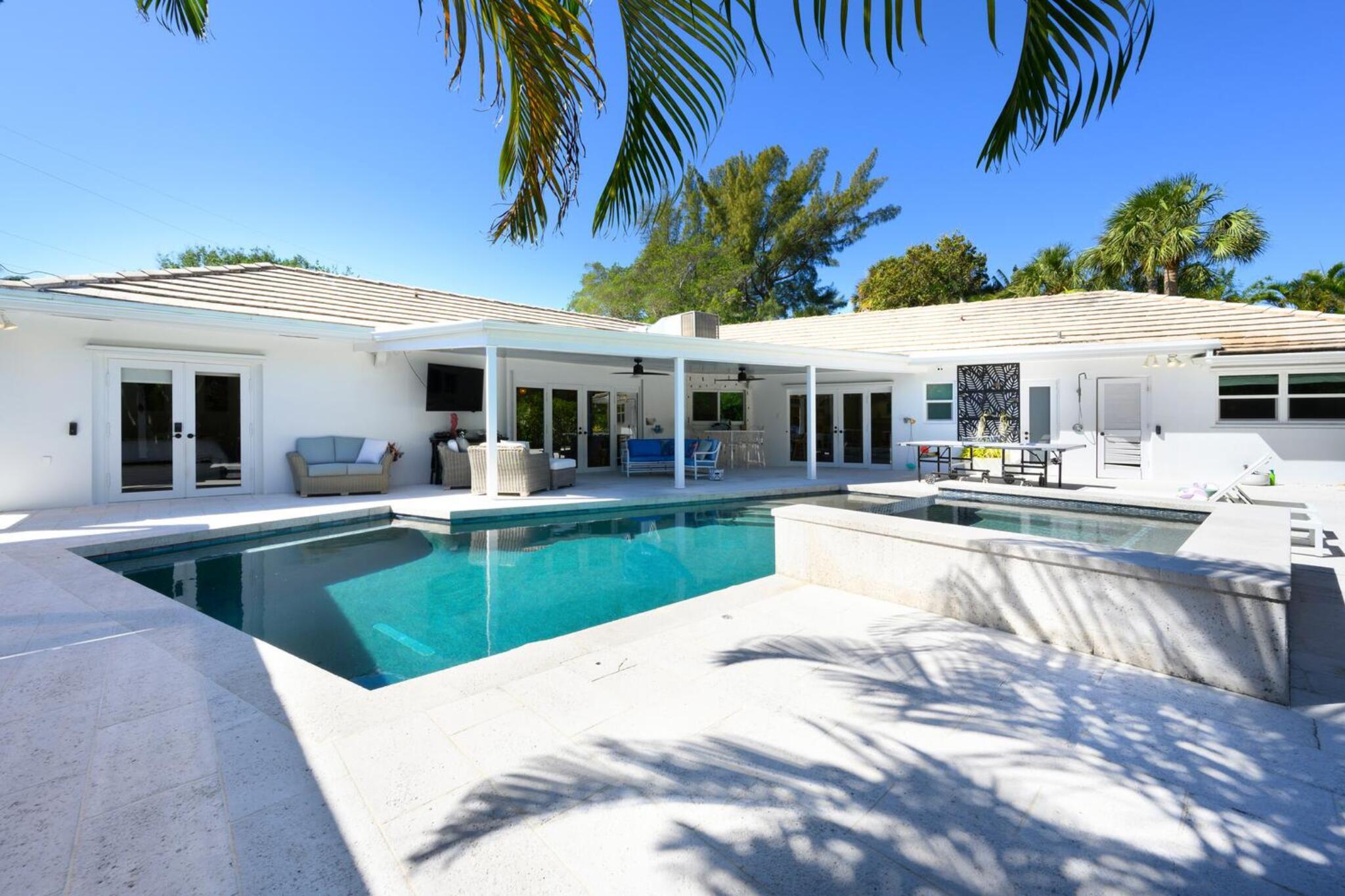 RARE WATERFRONT GEM IN PALM BEACH'S PREMIER NEIGHBORHOOD OF HIDDEN KEY! Tucked away in the exclusive, gated community of Hidden Key, this private waterfront retreat offers 0.4 acre of lush, tropical beauty. A true rarity, this home seamlessly blends elegance, comfort, and the best of waterfront living. Inside, a thoughtfully designed split floor plan features 4BD, private office, cozy family room, & an inviting living room with a custom fireplace & stunning Pecky Cypress ceiling. Designed for effortless indoor-outdoor living, every space flows beautifully to the outdoors. Step outside to your own Florida paradise covered dining area, sparkling pool & oversized patio all overlooking peaceful water views. The newly built dock accommodates a 28ft boat, jet ski & more as you head to the ocean Take the kids tubing right from your backyard in legendary Little Lake Worth. The lush, tropically landscaped yard is a private sanctuary filled with bamboo, orchids, and native foliage. Whether you're sipping coffee in the tranquil garden, dining alfresco in the summer kitchen, or unwinding on the oversized dock designed as an outdoor living space, every moment here feels like a retreat. A rare opportunity to own an ultra-private, waterfront haven in one of Palm Beach's most coveted communities. Call today to schedule your private showing!