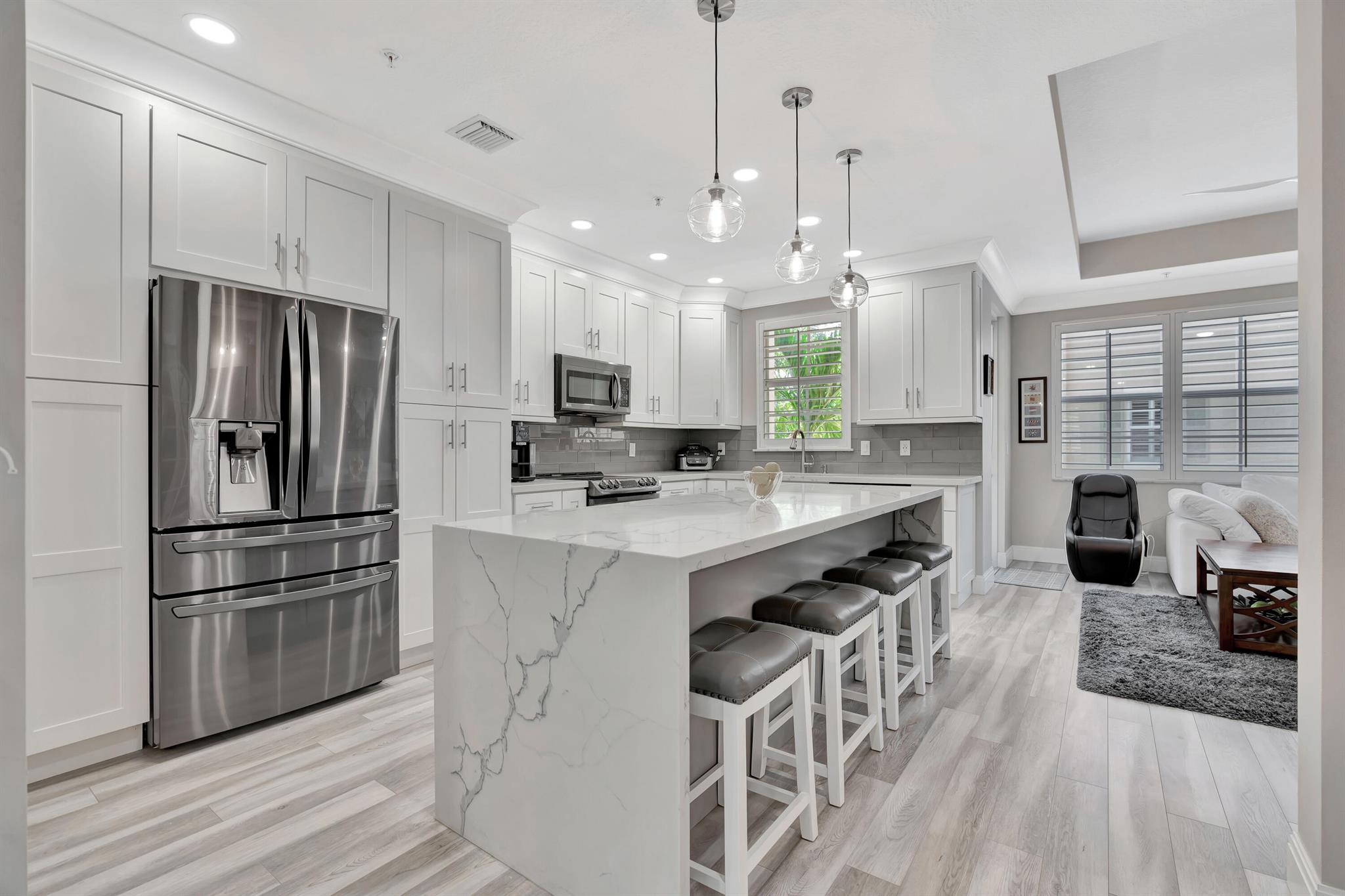 This stunning, completely renovated 3-story townhouse is truly one-of-a-kind and located in the prime spot of the development. Boasting 3 bedrooms, a den/office (which could easily serve as a 4th bedroom with an en-suite bath)  and 3.5 bathrooms, this home also features a spacious 2-car garage. Situated as an end unit, this Barcelona model offers exceptional privacy and panoramic lake views. The interior showcases exquisite laminate wood flooring throughout, adding warmth and elegance to every room. The updated kitchen is a chef's dream, with beautiful quartz countertops, a large island, and crisp white shaker cabinetry. The open living and dining areas seamlessly flow together, creating a spacious and inviting environment perfect for both everyday living and entertaining guests. The home also features custom wardrobe spaces, recessed lighting, tray ceilings, and plantation shutters that enhance the overall aesthetic.Relax on the covered balcony while enjoying the serene surroundings or take a short walk across to the community pool and clubhouse. Additional highlights include ceiling fans, a front-load washer and dryer, and the security and privacy of a gated community. Residents also enjoy access to a fitness center, community pool, playground and clubhouse, making this home the perfect blend of luxury and convenience.