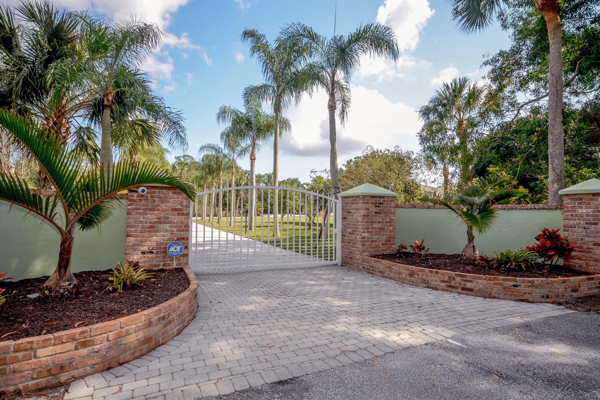 As You Arrive at This 2.5 Acre Jupiter Farms Property, You Will Be Welcomed Thru a Stately Gated Brick Entry Down the Palm Tree Lined 250' Paver Drive into a Hidden Spacious Sanctuary in Wildwood Acres.  This Large Remodeled 5-Bed, 4-Bath, CBS/Brick Home With 4 Stalls Features a New Roof, 2 A/Cs & A Whole House Generator.  On The Opposite Side of the House with Access from The Attached 2-Car Garage or the Breezeway Beside the Stables Are Two Air-Conditioned Rooms & a Full Bathroom.  This Could Easily Become an Income-Generating Self-Contained 1-Bedroom Apartment, In-Law Suite, Grooms' Quarters, or Home Gym / Office.  Adjacent to the Stables Is a 62' X 12' Dedicated Area for RV Parking with Electric & Water Connections.