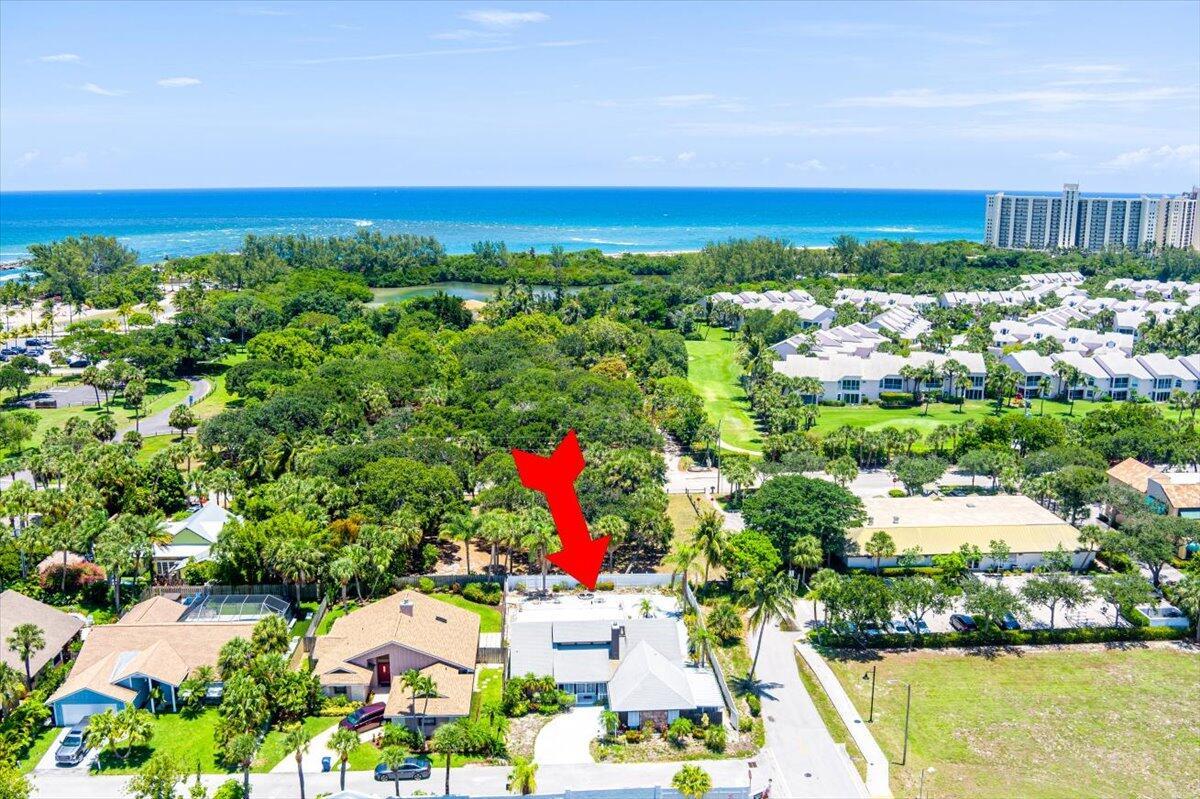 This is a rare opportunity to own a slice of paradise in a sought-after Jupiter location. Just steps from DuBois Park, Jupiter Beach, and the scenic Inlet, this charming single-family home offers coastal living at its finest.This beautiful residence features 3 spacious bedrooms, 2 full bathrooms, and a 2-car garage. Two expansive covered patios overlook a sprawling, fenced backyard with a sparkling in-ground pool--perfect for relaxing or entertaining. With no homeowners association, enjoy the freedom to make this home truly your own.A grand double-door entry sets the tone, opening into a bright and airy living and dining area with soaring volume ceilings and transom windows that bathe the space in natural light. The large covered patio seamlessly connects to the pool area, ideal for ndoor-outdoor living. The eat-in kitchen offers ample space for culinary enthusiasts, while separate laundry room adds everyday convenience. The thoughtful split-bedroom floor plan provides privacy and flexibility, one side of the house is ideal as a guest or in-law suite, while the spacious master retreat features a walk-in closet and an en-suite bathroom with a Roman tub, separate shower, and elegant vanity.
