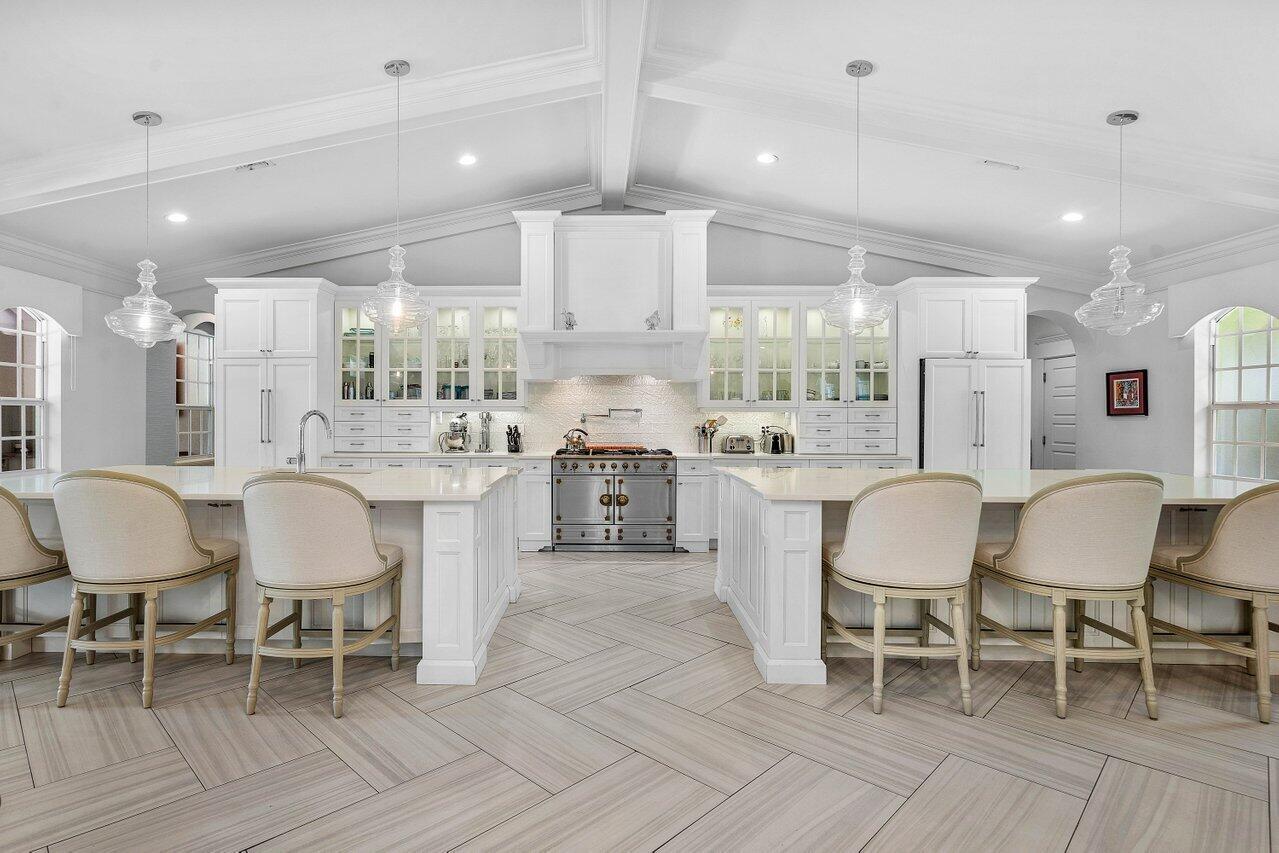 Situated on over one acre of land, this renovated and charming one- story home offers you phenomenal views with nearly 190 feet on the largest lake in Steeplechase!Featuring a modern open plan with traditional and modern details and classical finishes including a french style garden, brick paved circular driveway & boasting a stunning cathedral ceiling with beams and crown moldings as well as impact glass doors and windows and a newer roof.Once you walk through the double iron doors and just past the main living areas an outstanding custom built white kitchen is showcased with an abundance of upper glass cabinetry, an 11' high custom hood, white quartz counters and 2 large islands of 5'x9' each.  The focal point of this gorgeous kitchen is  a ''La Cornue'' stainless-steel/chrome/ brass range with a gas cooktop and 2 electric convention ovens. 
The primary bedroom boasts a sitting area overlooking the lake, french doors allowing for direct access to the pool, 2 large walk-in closets, a make-up area and a gorgeous ensuite primary  bathroom highlighting a free standing double ended cast iron tub with a view of a landscaped private garden, a seamless glass shower and separate custom vanities.  On the opposite side of home you will find 3 spacious bedrooms, 2 new full bathrooms, a laundry room with custom built-ins and a 3 car garage.  
Tucked away in a private spot in the beautiful backyard is  a lovely guest house with a full bathroom with custom vanity and 2 separate rooms with french doors opening to a deck overlooking the garden and the lake. 
Steeplechase is lined with beautiful oak trees and sidewalks, all homes in the community are on an acre or more with room for tennis / pickleball courts, sport courts, putting greens &amp; more! The community is centrally located w/in Palm Beach Gardens and includes a front and back gate as well as 24 hour roaming security.  Less than 15 minutes to the Gardens Mall &amp; area restaurants, 20 minutes from the PBI airport or Jupiter, 15 minutes from West Palm Beach and 25 minutes from the island of Palm Beach.
