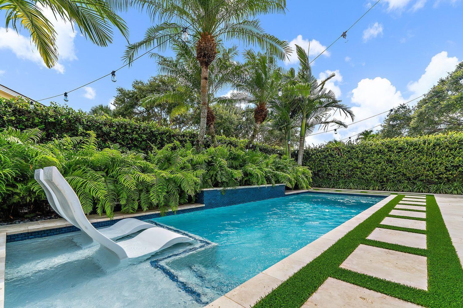 Feel the breeze! Highly desirable, southeast corner property in prime location in the Bluffs and close to beautiful Jupiter Beach. Embark on a delightful journey through this beautifully renovated home where subtle design choices make all the difference. The redesigned kitchen provides for a more formal arched entry leading to an open floor plan with serene views of the tropical landscape and beckoning pool. Enjoy the sophistication of Bosch appliances, white cabinetry with smart storage solutions, a custom hood, and stunning mosaic marble backsplash and counters. The accent shelving and brass details add a touch of understated luxury. Impact glass, new AC 2023, stunning salt-chlorinated pool w/sun shelf + sheer descent water feature completed in 2024, Oak wood-plank tile floors, vaulted