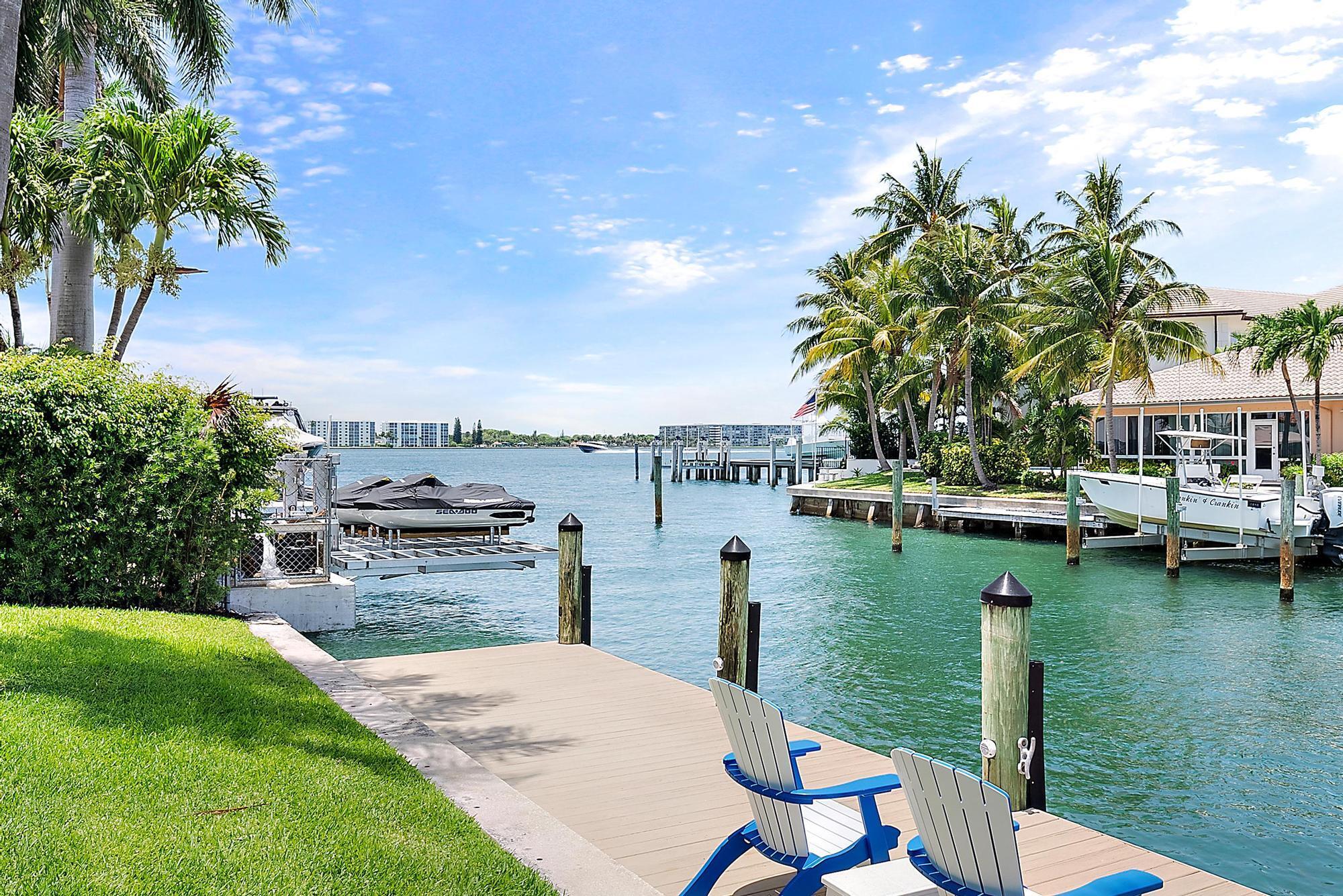 A BOATER'S PARADISE! A true gem in Palm Beach Isles, this rare waterfront home on Singer Island is just one lot from the point and offers beautiful views of the Intracoastal Waterway. This 4-bedroom, 3-bathroom home sits on an oversized 12,494 SF lot with 100 feet of prime water frontage. Tucked away on the cul-de-sac of prestigious Coral Way, residents enjoy exceptional privacy in this coveted enclave, accessed by the charming bridges at the community's entrance. The home has been tastefully renovated, featuring a tray ceiling in the great room that enhances the open-concept design, rich hardwood flooring, elegant bathrooms, and crown molding throughout. Boating enthusiasts will appreciate the 40,000 lb. lift, additional 2,500 lb. lift, and a large 66' x 8' deep-water dock accommodates all your yachting needs. A motorized pergola on the rear pool deck adds 525 SF of flexible outdoor living space&#x14;covered or open to the sun at your command. Additional features include a full-house water filtration and softening system, ensuring high-quality water for both your home and your boat. With no fixed bridges and direct access to the Palm Beach Inlet, effortless escapes to the Bahamas are just moments away.