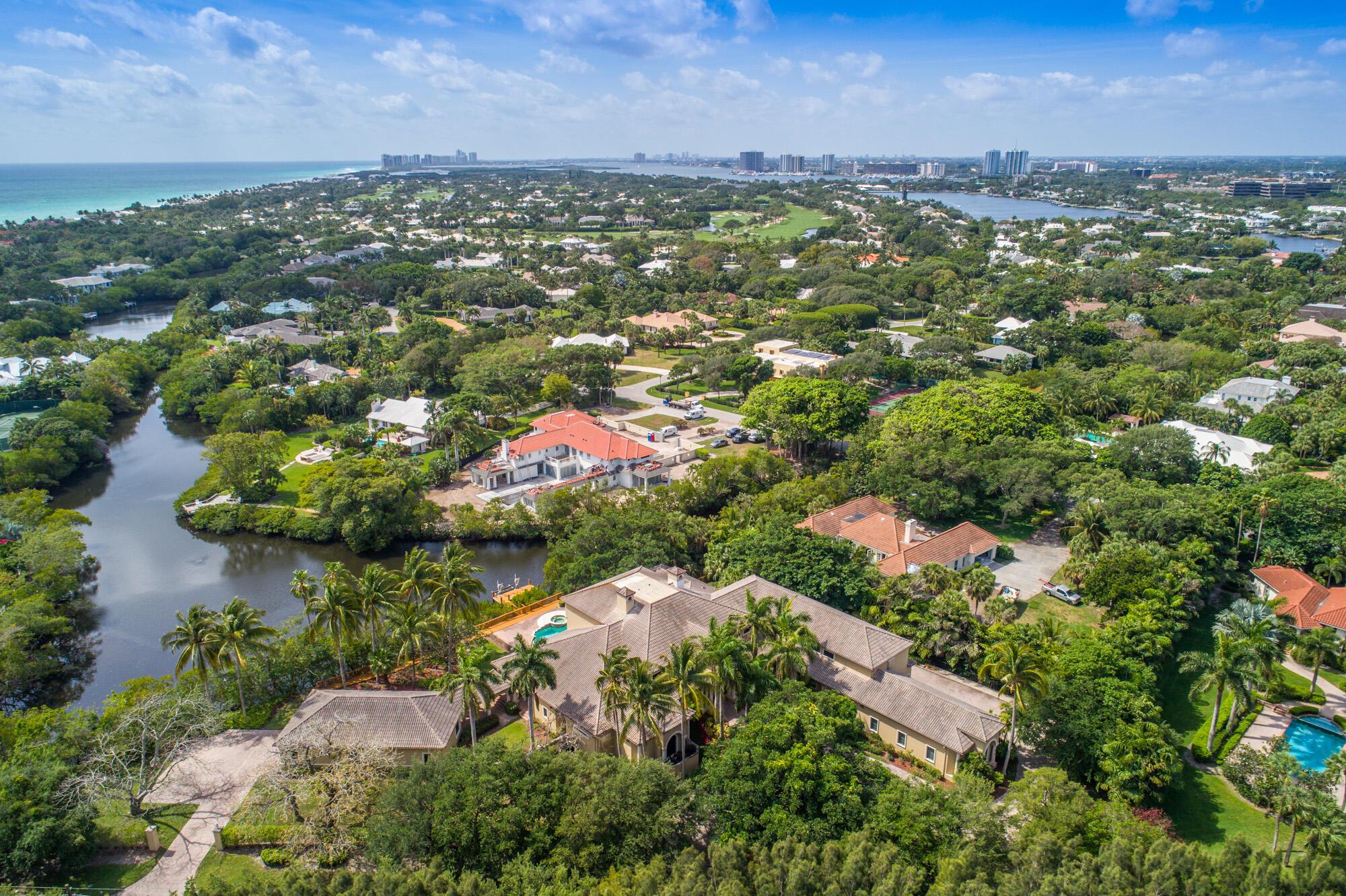 Discover an impressive 18,000 square foot residence, complete with a guesthouse, nestled on a generous 1.5-acre lot boasting coveted southeast exposure mere steps from beach access within the prestigious Seminole Landing community. Behold breathtaking views of the tranquil lagoon, canal, and preserve from this Mizner-inspired Mediterranean masterpiece! While maintaining its original charm, this home offers a spectacular floorplan with high ceilings and generously sized rooms that seamlessly transition to the expansive outdoor living area, featuring a saltwater pool, spa, and a private dock with a boat lift for smaller vessels. Enjoy the luxury of newer impact glass doors and windows, complemented by hardwood and stone flooring throughout. The spacious downstairs master suite boasts his an