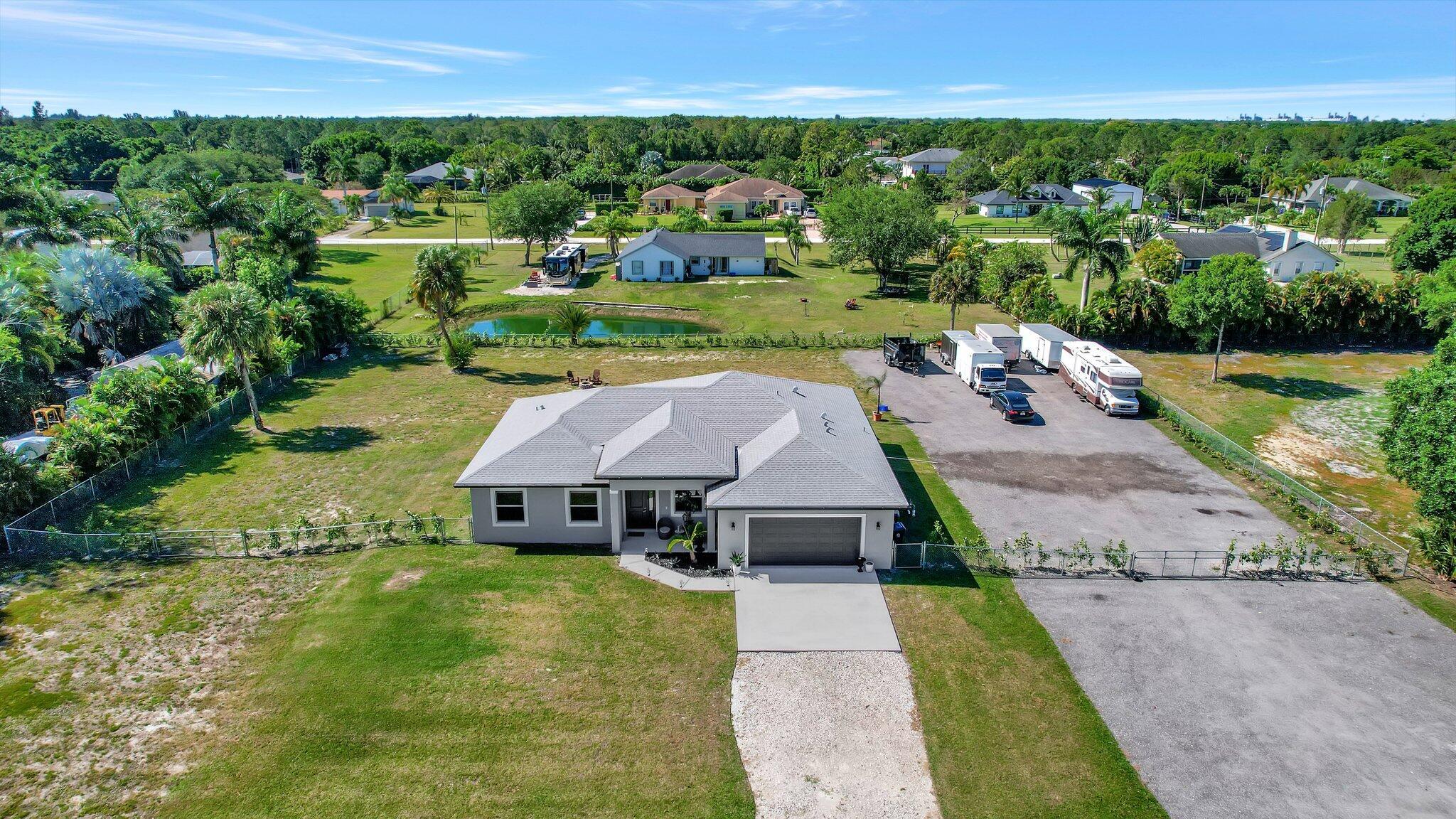 Beautiful home built in 2022 sitting on 1.15 acres that includes 4 bedrooms / 2 bathrooms / 2 car garage PLUS an additional den space. **IMPACT RESISTANT DOORS AND WINDOWS THROUGHOUT** As you walk in, you will notice the spacious layout of the home, with 10' ceilings and wood tile throughout. Lovely open concept living room area and kitchen space perfect for entertainment. The kitchen features white shaker cabinets, stainless steel appliances, quartz countertops, and plenty of counter space including the island. Split floor plan - airy primary bedroom that includes 2 walk in closets, and a gorgeous bathroom with 2 bathroom vanities, a walk in shower and roman tub. The whole backyard is fenced in with freshly planted clusia hedges that will provide an extra privacy barrier as they grow. Newly added paver patio space for outdoor entertainment! There is room for boats, RVS, trailers with the compacted gravel in place on the west side of the property. Everything is just like new in this home, very well taken care of!