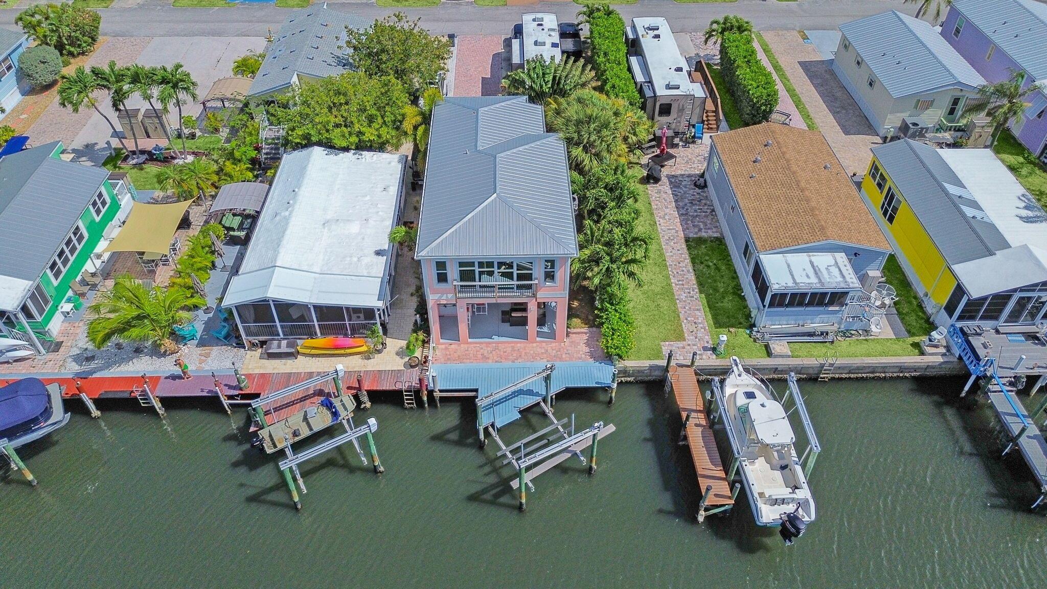 CUSTOM BUILT NEWER CBS WATERFRONT HOME!  KEY WEST STYLE LIVING ON HUTCHINSON ISLAND! Built in 2022 with impact windows and metal roof. This property boasts 30ft. of waterfront just shy of the intracoastal with a 10,000lb Neptune boat lift capable of up to a 30 foot boat. Huge lanai with a bar, refrigerator, sink, and even an outdoor bamboo shower. Well appointed kitchen with convection microwave and oven, dishwasher and induction cooktop. Tastefully appointed bathrooms featuring a rain shower in both and a double sink vanity in primary. This community offers a waterfront paradise with boating, community pool, beach access, and boat launch. Come experience the Florida lifestyle on Hutchinson Island featuring beautiful sunsets from the lanai, sunny beaches, nature preserves, golf, museums,