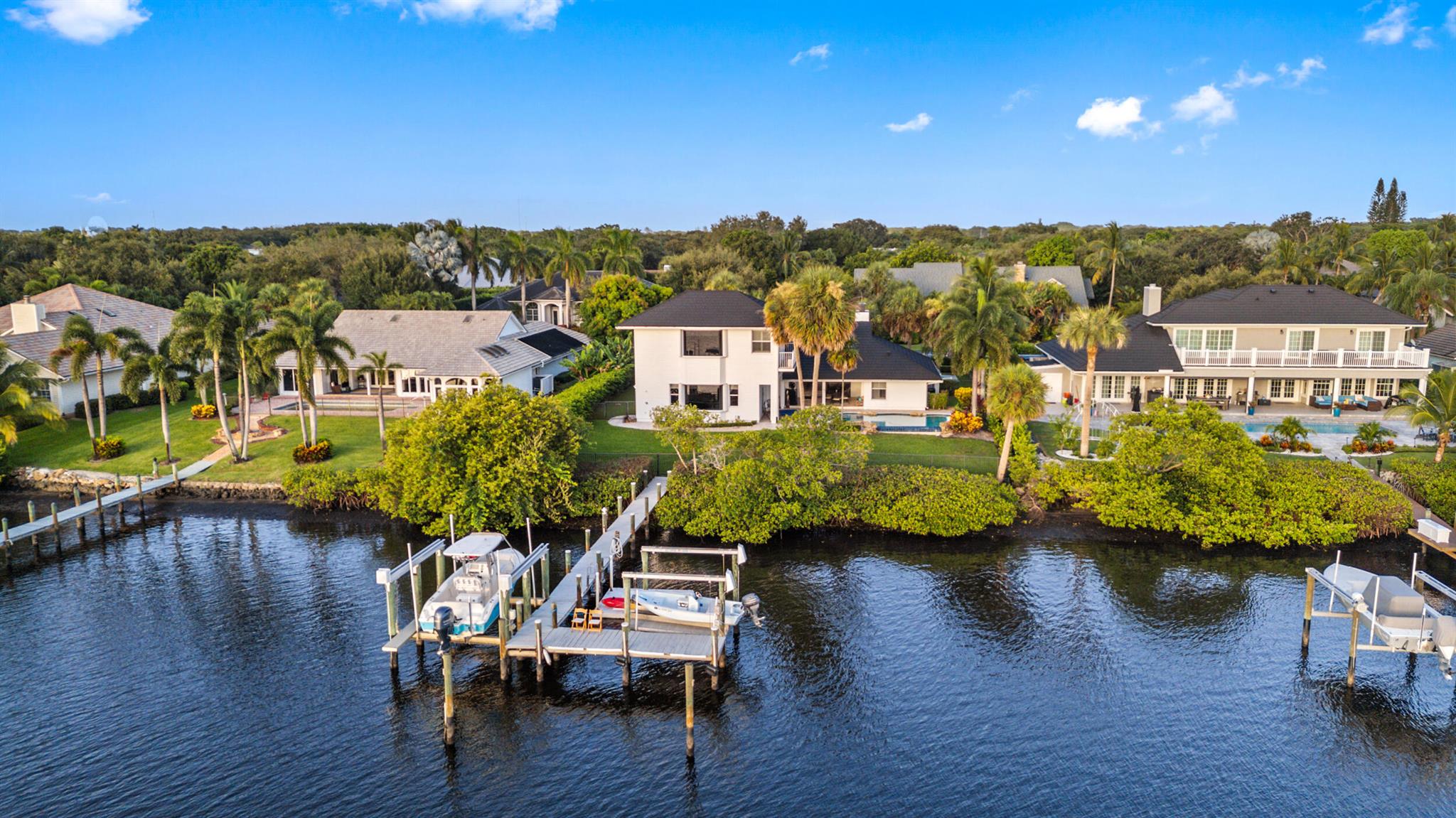 This coastal styled home is loaded with natural light and enjoys serene Loxahatchee River views with picturesque sunsets and beautiful reflections on the river at first light!The 16,000lb & 7000lb lifts will hold your boat or jet skis and are a scenic 15 minute ride to the Jupiter Inlet, a natural sandbar or a dozen quality restaurants.  The well maintained home includes these recent updates: new stone coated metal roof('23), all 3 ac units and upper level water heater ('22) , washer, dryer and pool pump ('21), tankless water heater, pool heater and all kitchen appliances ('16&'17). Porcelain tile throughout main floor, cozy semi private bar room with wet bar, wine cooler and kegerator.