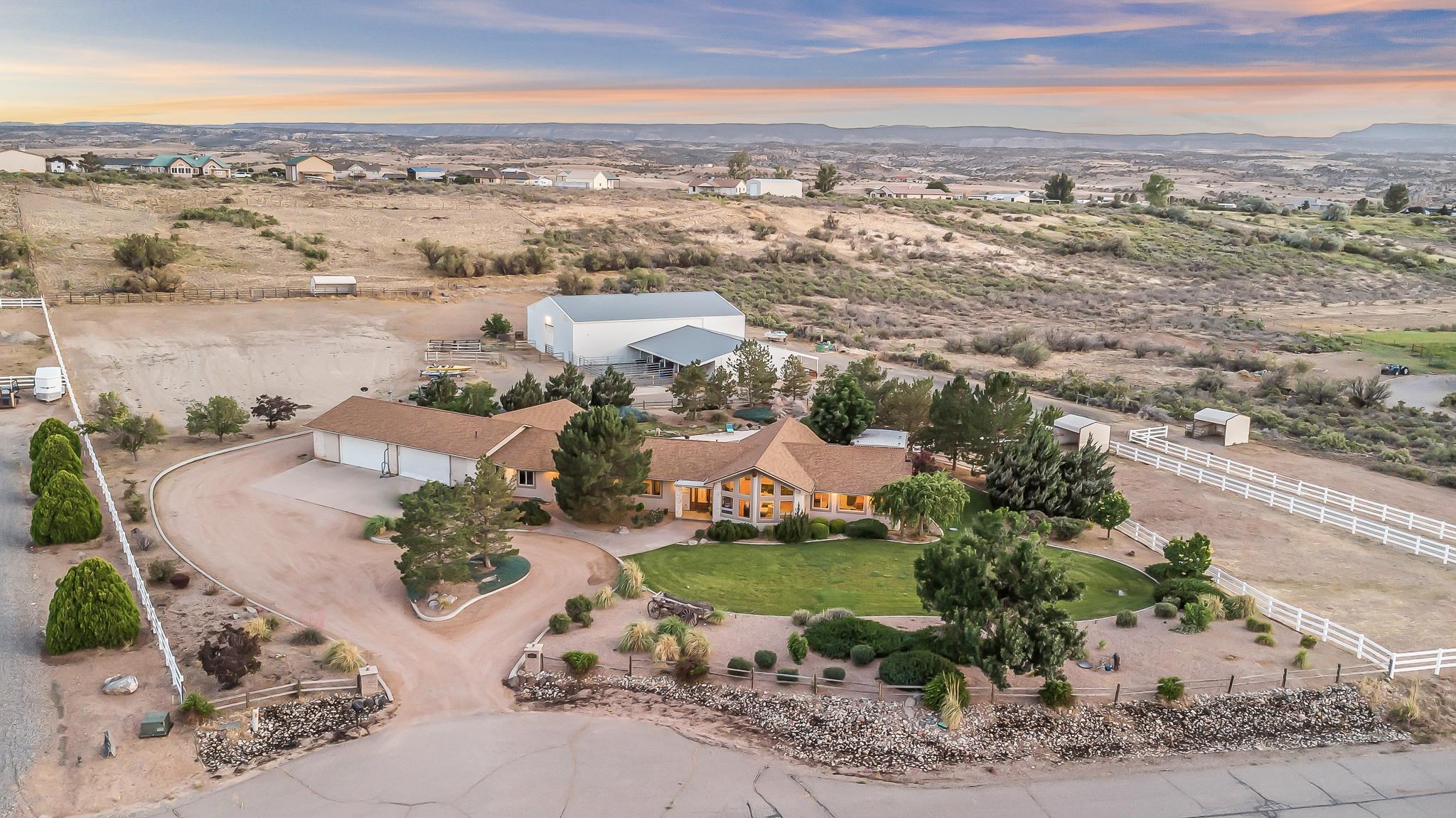 This eco-friendly custom ranch home offers country living with all the modern amenities. Located in beautiful western Colorado, this sprawling estate sits on 5.64 irrigated acres and features 3,565 square feet of open living space. Property highlights include vaulted ceilings, wood beams, reclaimed hardwood floors, expansive windows with stunning views, solar panels, geothermal heating and cooling, new roof in 2022, an in-ground heated pool with a waterfall, three bedrooms, an office, gym, and an attached ADU/in-law suite with a living room, kitchen, and bedroom/bathroom suite.  This equestrian estate also features a 60x80 indoor riding arena, fenced outdoor arenas with automatic horse waterers, and paddocks. Attached to the arena is a barn with four stables, a heated and cooled tack shed with a bathroom, and multiple large overhead doors for easy access. Close to BLM land and offering phenomenal views of the Grand Mesa and Bookcliffs, this home epitomizes the Western Colorado ranching lifestyle. This versatile estate would make a perfect primary residence, investment property, or event venue.  Pictures do not do this property justice - schedule your showing today to experience it in person!