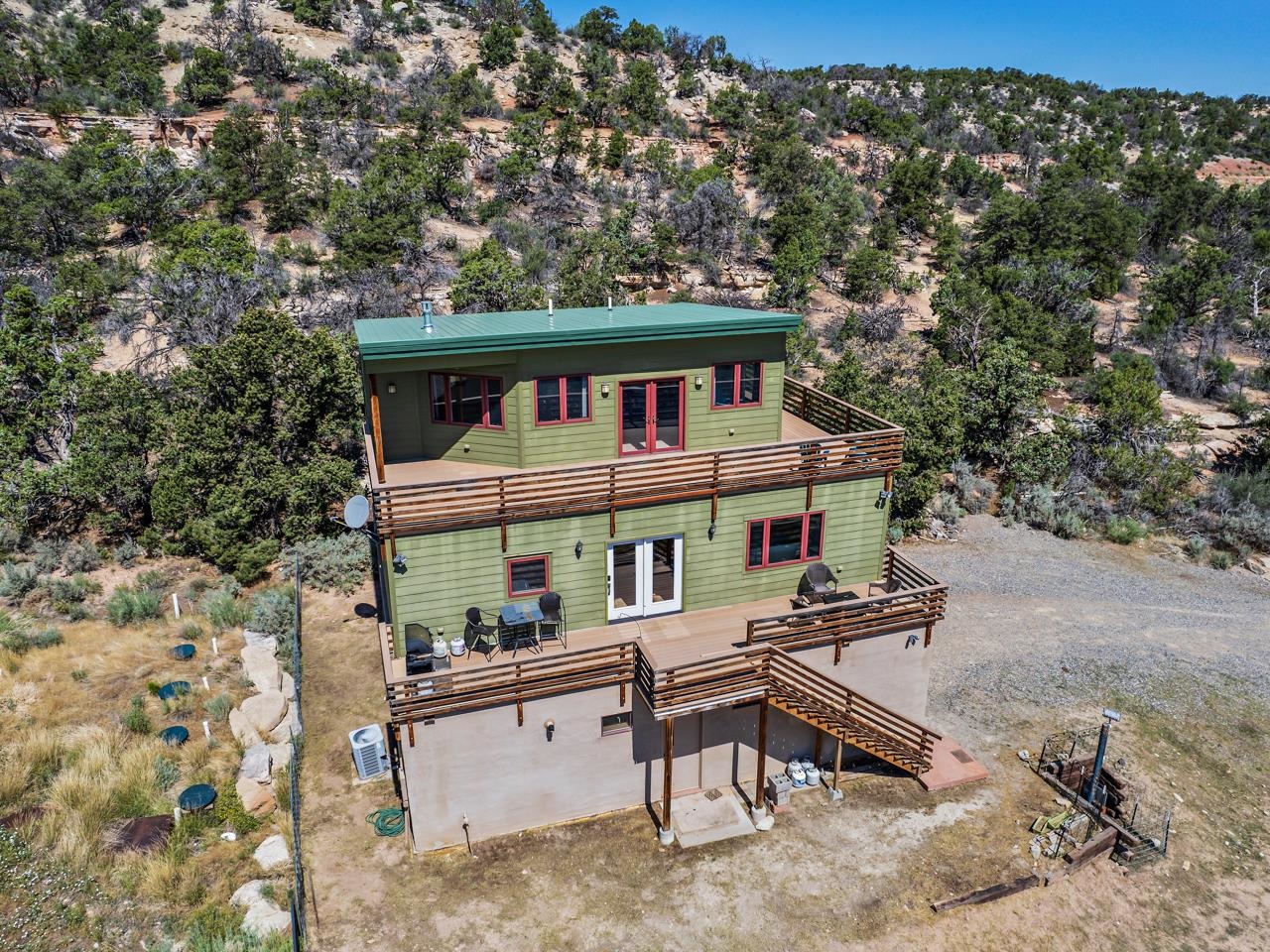 Would you like to experience the serenity, peace and security that comes with mountain cabin life + a bunker? Come see this property on almost fourteen acres of undisturbed land on the Colorado National Monument. Perfectly secluded, you’ll love the peace and  privacy of this property. Below grade, there’s a 1,400 sqft structure of concrete-reinforced steel walls with an extra 2300 cubic feet of storage. The underground shelter has 5 bedrooms, kitchen, bathroom, and ample living space. It comes equipped with an NBC (nuclear, biological, chemical) filter systems, power inverter with AGM batteries, 5 kw diesel generator, plus 500 gallon underground propane tank, and a main septic plus emergency septic systems. With two entry ways plus an emergency escape hatch, storage for 7000+ gallons of water, geothermal heating and cooling, and 3 bar structure to withstand extreme pressure, it has everything you need to live comfortably. Above ground at the main cabin enjoy sitting on your deck and being able to look out at all the views of the surrounding nature and mountains & hear every bird chirp in the unmatched quiet. The two decks will make you want to sit out and watch the sunrise with a cup of coffee. Not to mention both decks are made of Trex, making them low maintenance and very durable. Walk in and discover the well and naturally lit main area. The living space comes complete with the perfect cabin-esque feature - a free standing gas fireplace. The easy flow of the space allows quick access to the kitchen, and dining area. The kitchen contains all the important amenities, and includes a sit up counter at the island. Two well portioned additional bedrooms are just off the main space, and offer easy access to the four piece bathroom (which comes with a bidet). Head up the stairs and be wowed by the large primary suite. It comes complete with another free standing gas fireplace, the perfect wood accent pillar, and most importantly a view. Imagine waking up to such beautiful views. You won’t want to leave your bed! Access to a walk-in closet and three quarter en-suite bath just complete the package. The oversized basement garage has a colossal amount of storage space and plenty of parking for any vehicle enthusiast, or use it for any major project you can undertake. There is certainly room down there! This is a unique and unmatched find. Come experience your own slice of secure mountain paradise. Schedule a showing today!