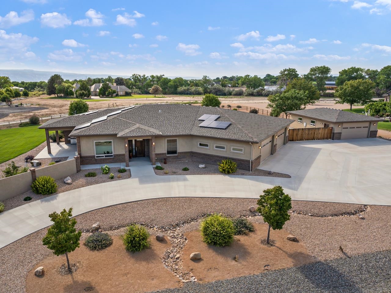 Come & see this beautiful & immaculate home in the desirable North area of Grand Junction. Located in the peaceful L&M Estates, you’ll find this house is ideally located for a nice, quiet lifestyle. First thing you will notice is the surrounding views! The Book Cliffs, & Grand Mesa right out the front door, & the Monument right out the back, the scenery is nothing but spectacular. The xeriscaped front yard is low maintenance & eye-catching as you stroll up to the home. The front of the home is also very easily accessible to all with no steps leading in & 36" width doorway. As you enter the home you’ll see a huge living room that absolutely capitalizes on the natural light from the large windows. The space has beautiful engineered hardwood flooring with knotty alder trim & gas fireplace that ties the room together. An office just off the living room comes with abundant space & is complete with built-in cabinetry made of that lovely knotty alder. The flow to the informal dining area & kitchen is excellent. The kitchen has a ton of cabinet & counter space, a sit up breakfast bar, an island, solid surface countertops, stainless steel appliances, ample electrical outlets, & an enormous pantry. Off the dining space are two well portioned additional bedrooms with lots of closet space & easy access to the full bathroom. The generously sized primary suite comes with a large walk-in closet & access to a four piece en-suite bathroom with a no step steam shower, & a dual vanity. A mud room in the back of the house provides access to additional storage, a half bath, & the massive four car garage. The garage offers radiant in-floor heat and is the ideal spot for all vehicle enthusiasts, those with lots of toys, or anyone with projects on their mind. In case you need further space & options there is an additional 24’x 36’ detached garage/shop. There is also an RV pad with electrical, water, & septic dump. The backyard has lots of room to roam & is beautifully landscaped. The patio is the ideal spot to relax as it provides shade in the summer & sun in the winter, it also includes an outdoor fan for airflow, a speaker system, & not to mention a hot tub to soak those cares away. The home is very energy efficient with owned solar, back up battery to power the home in an outage, tankless water heater, radiant floor heating, & a central vacuum for easy clean up. There is so much to see at this property. You will absolutely love it! Schedule a showing today!