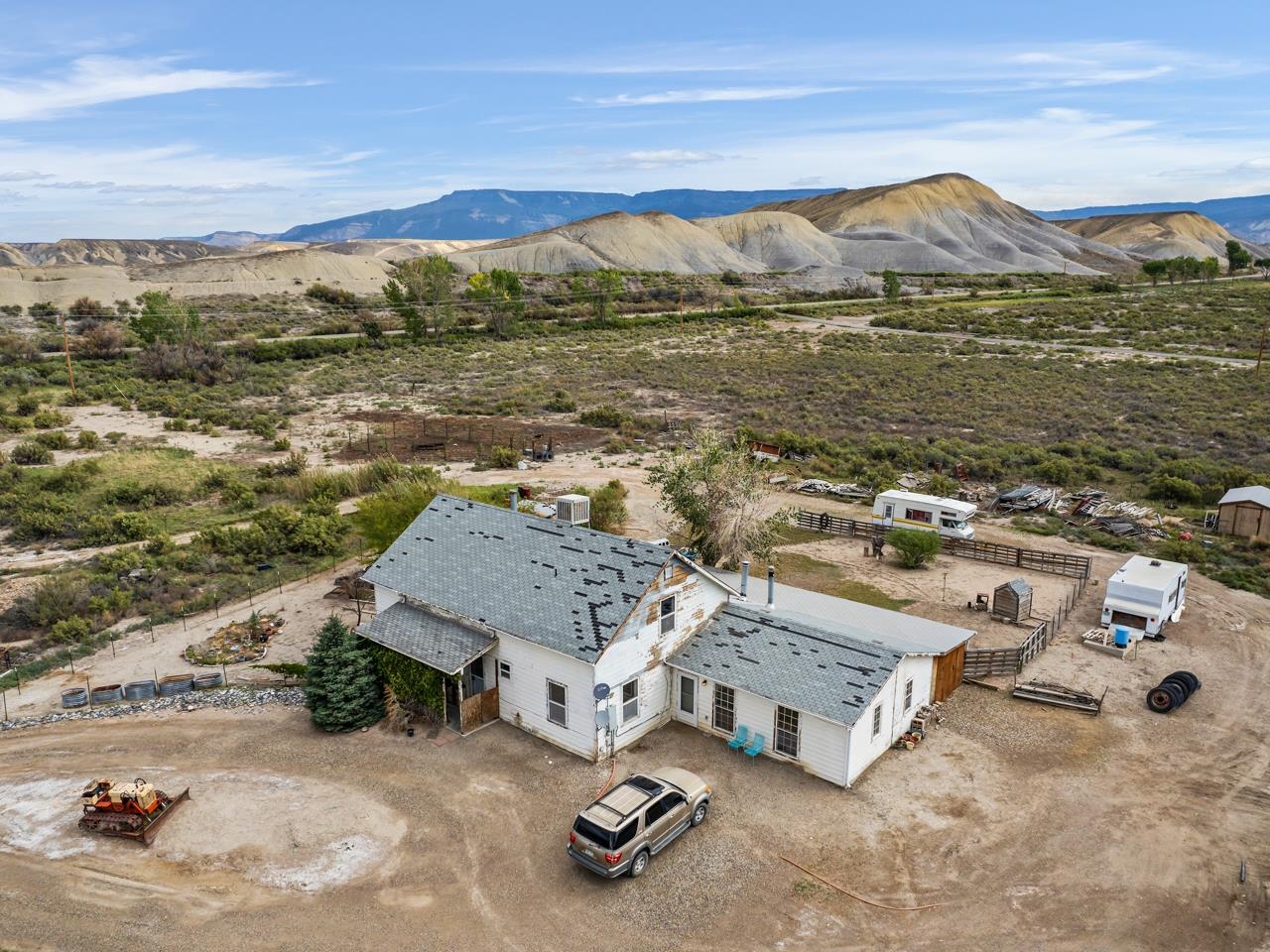 A private and secluded home on 9.21 acres awaits to make it yours! Located in Whitewater, this home is just a short drive to Grand Junction or Delta for everything you need. You’ll certainly enjoy the views of the mountains that surround the home, and the non crowded feel of the area with part of the property bordering public land. The acreage of land delivers lots of room to stretch out and call your own. The home itself has endless possibilities given a little TLC. The front patio is mostly enclosed with some lattice, and the driveway has lots of room for any vehicle(s). When you step inside you immediately notice the cathedral ceilings and the good amount of light that pours in through the windows. A loft overlooks the main living space and leads to a full bathroom and a large bedroom that has the possibility to be the primary given the space and closet. It certainly makes for a nice retreat regardless. Back downstairs, the kitchen has lots of wooden cabinet space, and all the essential appliances. The laundry/utility room comes with sufficient shelving and has access to the kitchen, side room, downstairs bedrooms and additional bathroom. A converted porch is a great spot for extra storage, but also can be an additional kitchen as it comes with added appliances and an antique stove! Off the side room is an added extra living space with hardwood floors and an alluring/intriguing stone pellet stove. The backyard comes partially fenced, includes a small storage shed and is ready to be developed. With great bones, this home is certainly a unique opportunity to polish it up and put your twist on. Come see it today!