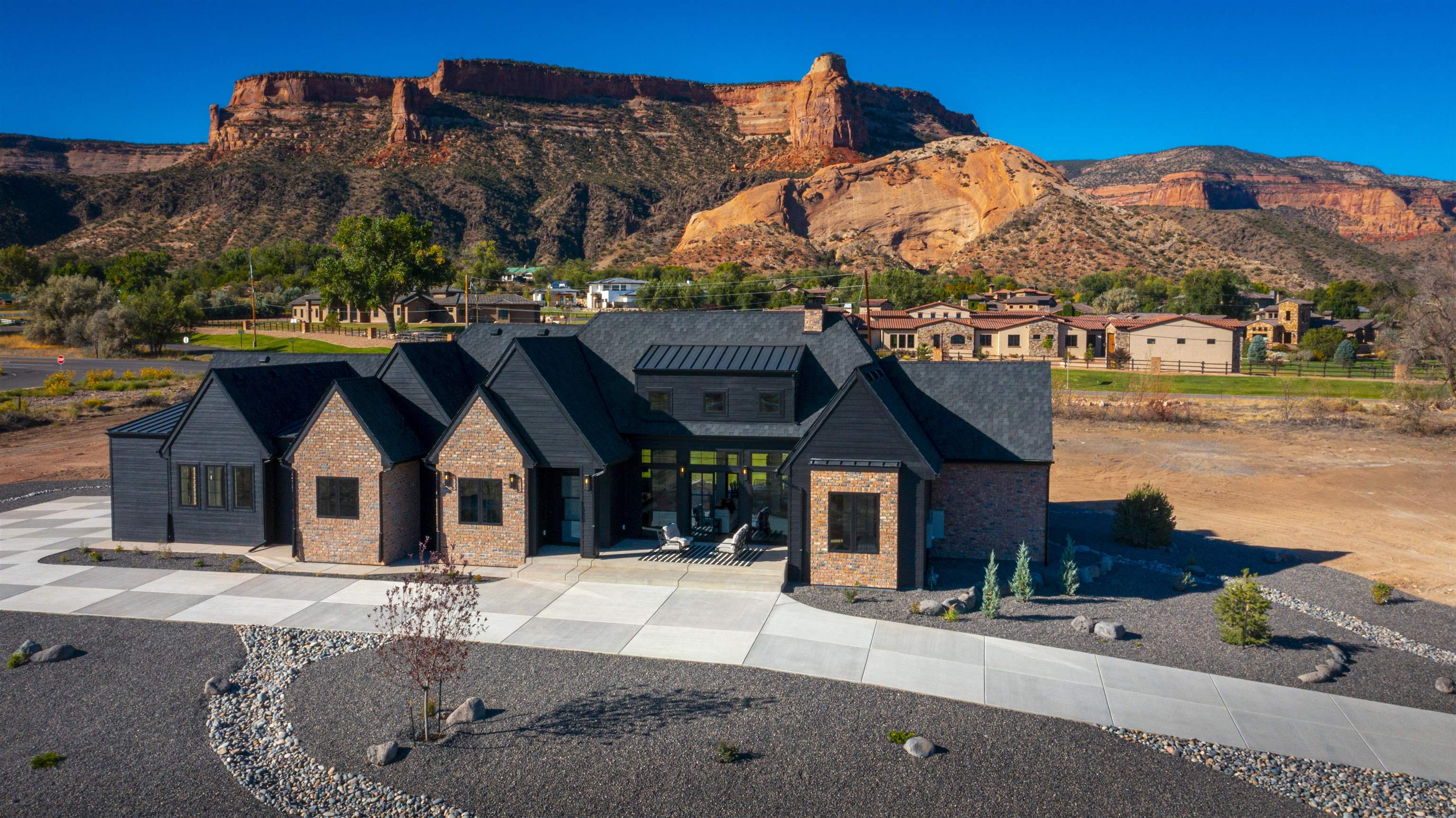 Midnight Manor in the 2024 parade of homes is now available for sale! Its bold architectural design boasts 16/12 roof lines, black siding, and auburn brick that mimics its backdrop of the Colorado National Monument. This home sits on 1.52 acres, offers 4 bedrooms + an office, 3.5 bathrooms and a is filled with luxurious high end finishes. From the moment you walk through the iron magic glass door you'll be welcomed to a sprawling open floor plan with extensive natural light, numerous vaulted ceilings, white oak beams and cladding, accent brick walls, taj mahal quartzite, and a true chefs kitchen and butlers pantry with 3 islands and 3 ovens. The home is equipped with Thermador appliances, surround zone and zone audio throughout, a built in DCS BBQ grill, fully custom cabinetry, and much much more. With prominent warm touches and daring bold finishes, this home exemplifies beauty in a multitude of styles. Welcome to Midnight Manor.