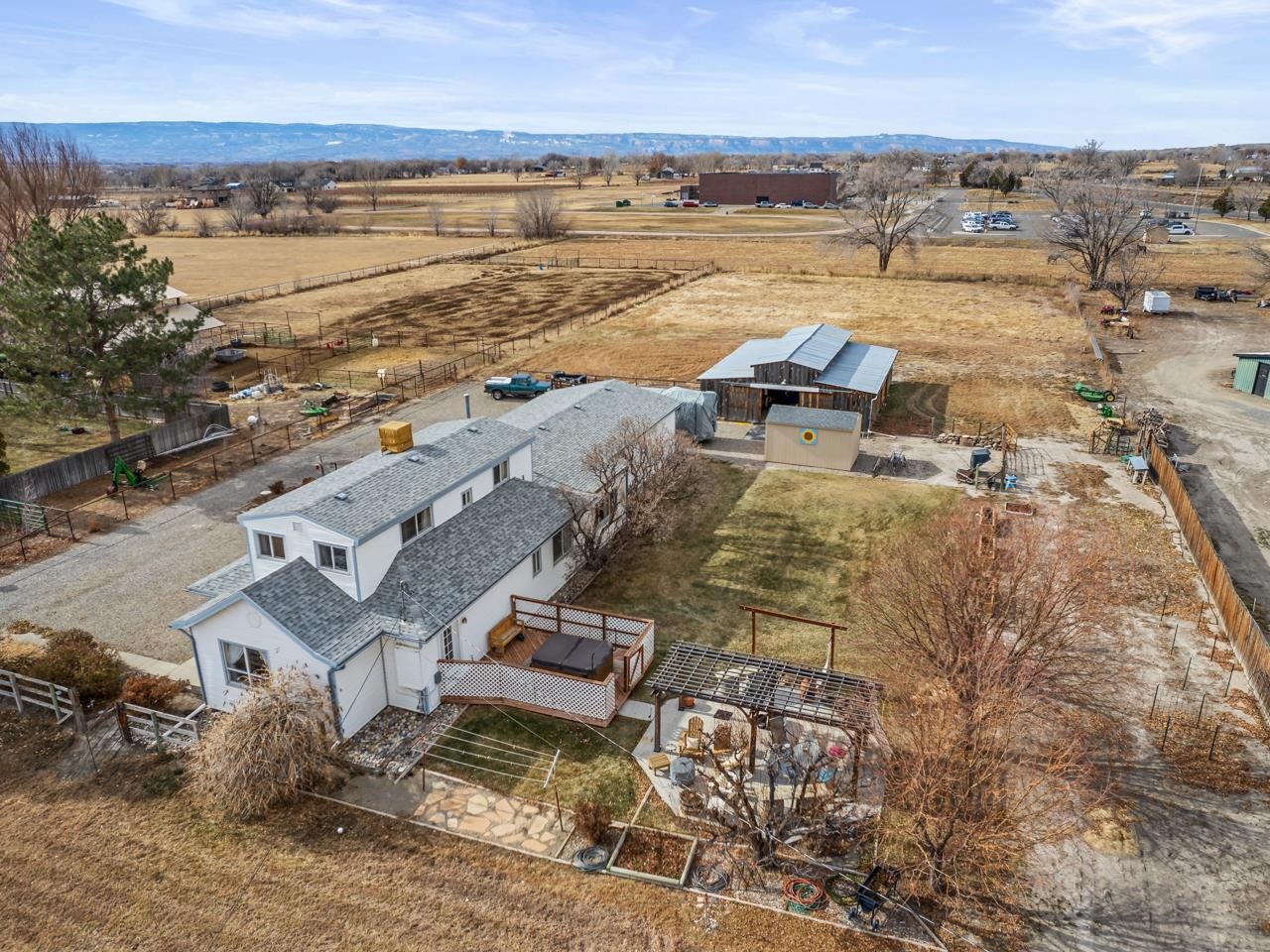 Welcome to the ultimate in country escapes - where charm meets dazzling views and endless possibilities! Nestled on a spacious lot with panoramic sights of the Grand Mesa and Mt. Garfield, this property is the perfect backdrop for your dream hobby farm. Located just a stone's throw from Palisade and Clifton, yet tucked away in a peaceful, secluded setting, it offers the best of both worlds. Step inside this delightful home and immediately be drawn to the welcoming den - complete with stylish fixtures, a beverage fridge, and plenty of room to gather and be your entertainment hub. Just off the den, discover the ideal crafting space (or whatever your heart desires) - a canvas for your hobbies or projects. The kitchen and dining area displays that aforementioned country charm with granite countertops, a unique tile backsplash, and ample cabinet space. PLUS, the kitchen is plumbed for a gas stove conversion! The main living room lets plenty of natural light, has access to the upper level, and a good spacious feel. Tucked away behind rustic paned doors, you’ll find a perfect little office space with direct access to the yard. On the main floor, you'll also find two comfy bedrooms (one with a walk-in closet) plus a full bathroom and convenient laundry room. Upstairs, enjoy a spacious primary bedroom with built-in shelving, a half bath, and an additional bedroom. Now, let's talk about where it all comes together for this property - outside, the possibilities are endless. An open deck with a hot tub offers the perfect place to relax and take in those epic Mesa views, while the pergola-covered patio invites you to dine al fresco or enjoy a sunset beverage. The large barn/workshop is the stuff of dreams - classic in style with endless space for all your equipment, or storage needs, plus a shop area. And don’t forget the expansive pasture, ready for animals, planting, or simply enjoying the wide open space. If you’ve ever dreamed of living the peaceful, wide-open country lifestyle, this is your chance. Come see this opportunity for yourself and start imagining your life here!