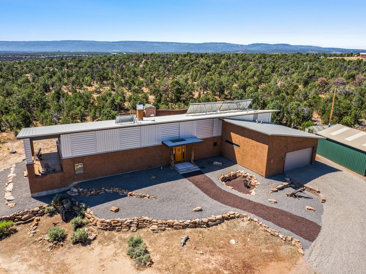 Experience sustainable luxury in this stunning Earth brick home on 34.5 acres in Grand Junction, CO. With a HERS rating of 8, its eco-friendly design ensures energy efficiency and year-round comfort. Nestled along scenic Little Park Rd and bordering BLM land, and The Ribbon Trail, outdoor adventures—hiking, biking, and off-roading—are just steps away.  This 3-bed, 2-bath retreat showcases artistic touches, from twisted beetle kill accents to colorful tilework and bottle art. The open layout, soaring ceilings, and passive solar design highlight breathtaking views of slickrock canyons, the Grand Mesa, and the Grand Valley. The primary suite features walk-in closets, a clawfoot tub, and a steam shower with backlit onyx.  Enjoy panoramic vistas from the covered deck or hot tub. The oversized 2.5-car garage, barn, and additional shop provide ample space. Sustainable features include multiple solar arrays, a rainwater collection system, a xeriscaped yard, and a walled backyard with a fire pit and garden.  With 400A service, a central vacuum, and a metal roof designed for water collection, this is high-desert living at its finest.  Come tour this home today!