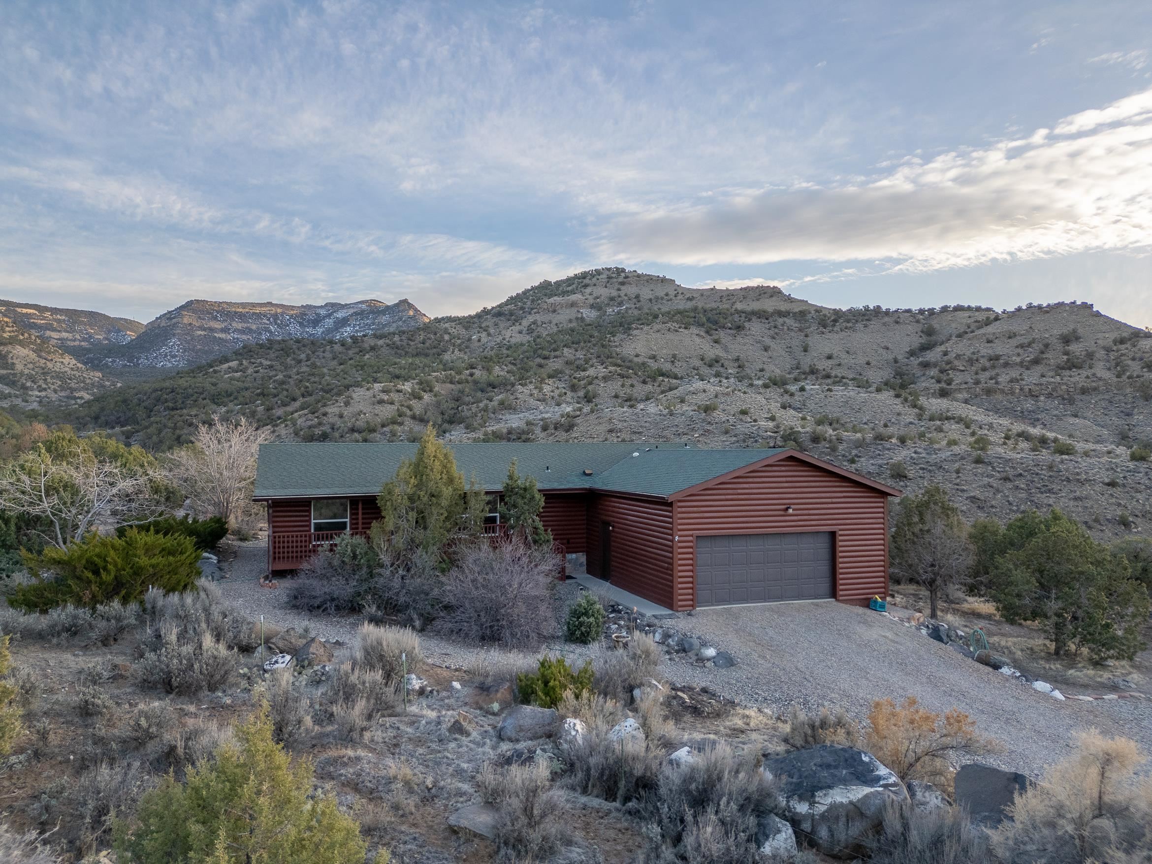 This is a sweet property.  Boasting 3.94 AC, this is mountain living only 7 minutes from downtown Palisade.  At the very end of Rapid Creek Road, privacy is a given.  Find pride of ownership in this 1490 sq ft, 3 bed, 2 bath, 2 car garage home that includes a huge master with walk-out deck access, an office/bedroom with a ton of light, a large kitchen, and a large pantry/laundry room that was designed as a craft area. The property borders private government land on two sides and is a few short steps away from BLM land.  Did I mention views?  The South facing side of the home is on a bluff overlooking Rapid Creek that offers wildlife shows on a regular basis, enjoyed from your partially covered back deck that spans the length of the home.  Listen to Rapid Creek flowing right below your bedroom window in the summer, and see views of the Grand Mesa that you will not see anywhere else. This property is something special.  Call for your showing today!