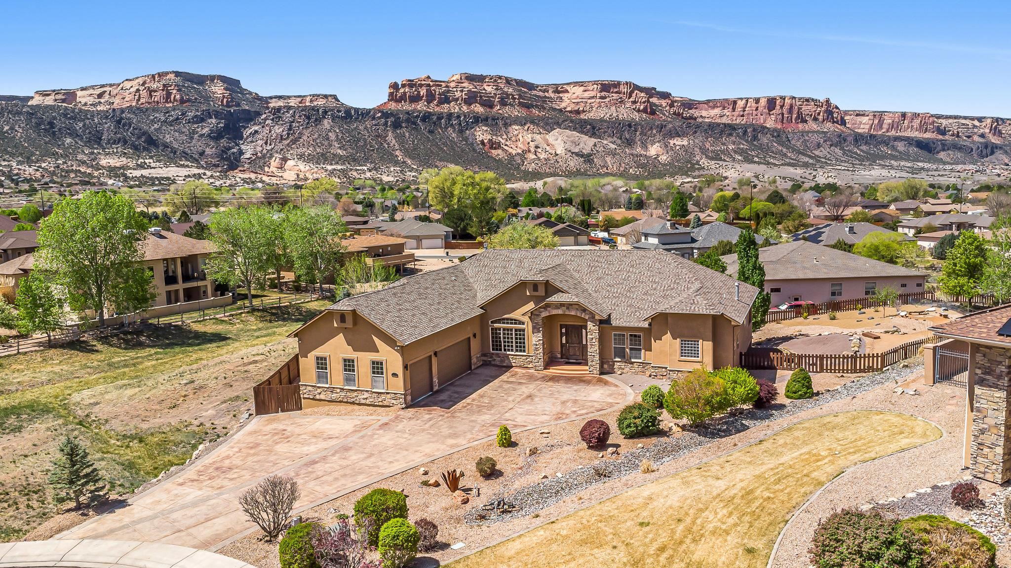 A Rare Redlands Retreat | 370 Teegan Court, Grand Junction, CO  Welcome to 370 Teegan Court—an extraordinary residence tucked into one of Grand Junction’s most prestigious Redlands neighborhoods. Set on over half an acre with stunning Monument views, this ranch-style home with a finished walk-out basement offers more than 5,500 square feet of beautifully designed living space.  Inside, you'll find a thoughtful split-bedroom layout on the main level. The spacious and serene primary suite includes a cozy fireplace, direct access to the back balcony, his-and-her closets, and a luxurious ensuite bath with dual vanities, a soaking tub, and a walk-in shower. Two additional bedrooms share a Jack-and-Jill bath and offer generous space and natural light.  The main floor also features a welcoming living room with fireplace, a formal dining area, a dedicated office, a half bath, and a light-filled kitchen with a dining nook—perfect for everyday comfort or entertaining guests.The kitchen is beautifully appointed with a high-end Wolf gas cooktop that elevates your culinary experience.  Head downstairs to be wowed by the expansive finished basement, designed for fun and relaxation. A fully-equipped theater room (seating and equipment included), game room with pool table and wine fridge, home gym with mirrored walls, and a family room with a fireplace and wet bar make this space truly one-of-a-kind. Two additional large bedrooms and a full bath complete the lower level.  Step outside to enjoy panoramic views from both upper and lower decks. The lush, mature landscaping, garden beds, RV parking, and surrounding open space create your own private oasis. Bonus features include a hot tub, sauna, swing set, and charming playhouse—offering something for everyone.  In 2025, the home underwent a thoughtful remodel, including new interior and exterior paint, a refreshed stucco exterior, foundation piers, new carpet throughout, updated basement flooring, and landscaping upgrades. And with 35 owned solar panels (installed in 2020), your energy efficiency is already built in.  Homes like this don’t come along often—make 370 Teegan Court your forever home.