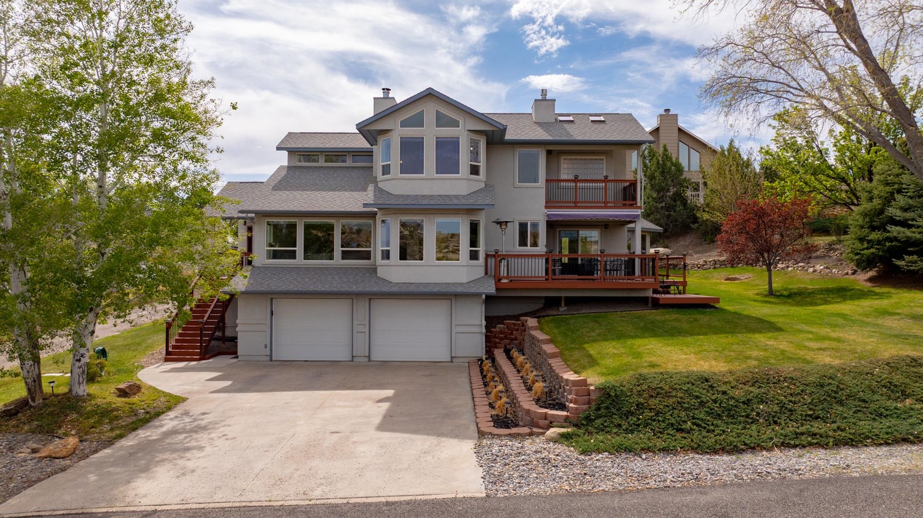 Welcome to the Ridges! This home sits on a hill with expansive views of The Ridges and the Colorado National Monument. The primary bedroom offers a gas fireplace, a large 5 piece bathroom, a deck looking west at the exceptional views, 2 walk-in closets or use one as an office, and new carpet. The kitchen and dining room have large windows facing west and another deck with a standing heater to enjoy the scenery year round. In the large living room sits a wood burning stove and 4 oversized windows. This home has been well cared for and including many NEW updates. Updates include interior paint, moldings, faucets, laundry room sink, decks, light fixtures, 1/2 bathroom, LVP, tile, carpet and more. The 1/4 acre has mature trees and plenty of back yard space and the garage is heated and extra work space for handy people. Oh, if you have a truck it will fit in the garage. Home is close to hiking trails, pickleball and parks and close to the end of the street.