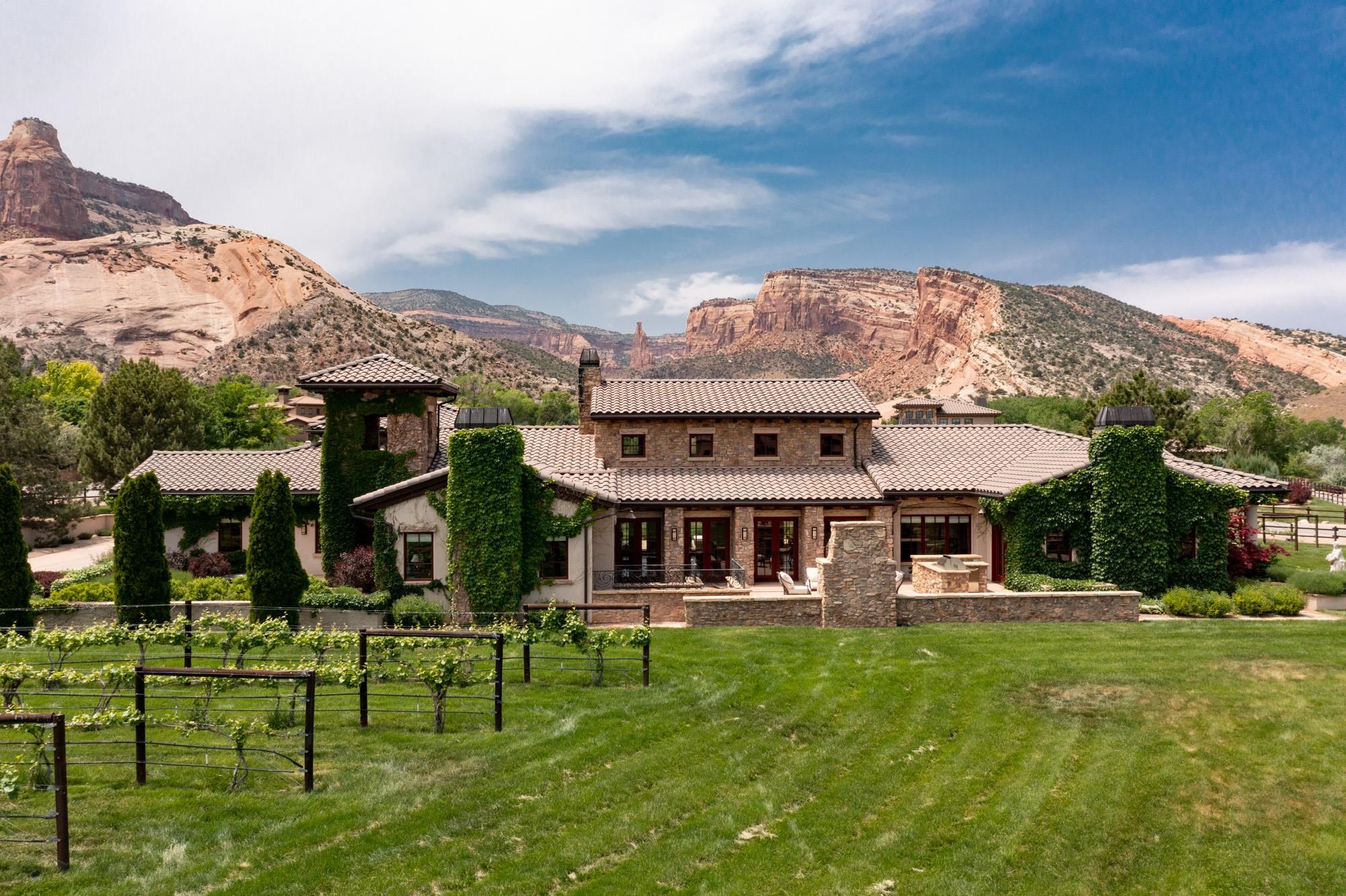 This magnificent estate located at 1954 Stone Canyon Court in Grand Junction, CO offers breathtaking unobstructed views of Independence Rock and the Colorado National Monument. The main house boasts just under 6,000 sq. ft. of luxurious living space, and there is an additional 836 sq. ft. detached Vintner's Cotttage that is perfect for guests or a caretaker. The property includes a private vineyard that offers the the opportunity to savor the fruits of your own labor and create your very own vintage wine.   As you enter the main house, you will be greeted by vaulted ceilings in the living room and stunning views of the mountains. The home features seven cozy fireplaces, including one in the outdoor kitchen that is perfect for entertaining guests. The travertine bathtub and bronze sinks in the bathrooms add a touch of elegance to the home.  The gourmet kitchen is equipped with high-end appliances, making it perfect for cooking and entertaining.   The owners suite has its own private patio where you can enjoy stunning views of the Monument and vineyard. The outdoor living space features many large patio areas with picture perfect views in all directions.  This is a once-in-a-lifetime opportunity to own a stunning estate with a private vineyard in a prime location. Don't miss out on this amazing opportunity to own a piece of paradise in Grand Junction, CO.