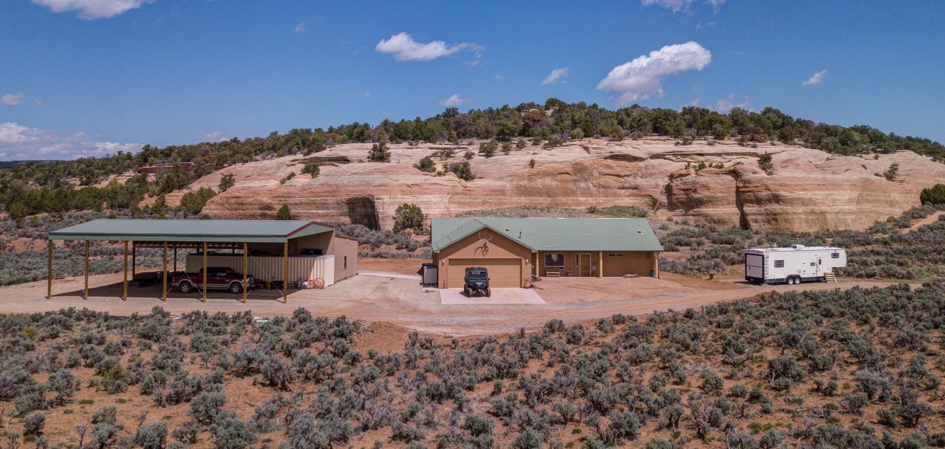 Perched on a rare 39+ acre bluff in Glade Park, this property offers a tranquil retreat, adjacent to an additional 20 acres of BLM land. The open living area features a split bedroom plan, while the kitchen boasts KitchenAid appliances, upgraded cabinets, & pullouts. Stay cozy with a pellet stove, & retreat to the primary bed with scenic views. The luxurious primary bath showcases an Aquatic jetted tub and oversized walk-in shower, adorned with onyx & travertine finishes. Outside, a 60x36 pole, 26x24 workshop provide ample covered parking for RV with 30 amp while a private walking path surrounds the property. Enjoy wildlife from the covered patio or sunroom. Added features include reverse osmosis & emergency fresh H20 tanks. Don't miss out on the luxurious upgrades throughout.