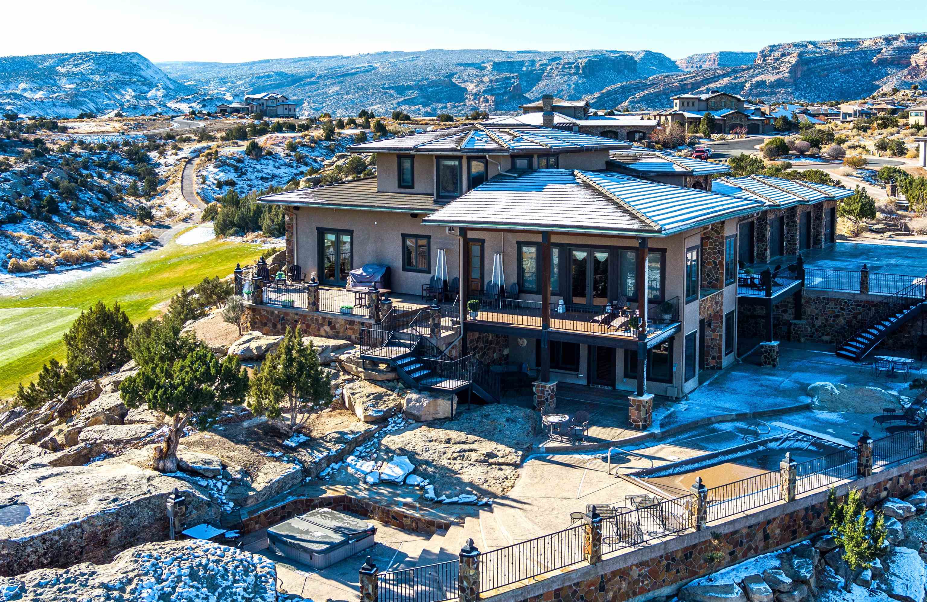 This elegant home is perched above 3 fairways overlooking town and the surrounding mountains. Sitting on .58 acres of one of the most desirable lots in Redlands Mesa, the 360 views are breathtaking. Along with the views, the lot provides privacy you won’t get anywhere else. Entering the home the grand living room shines with a large stone fireplace, hardwood floors, exposed beams and wall to wall picture frame windows overlooking Redlands Mesa Golf course. The chef's kitchen is equipped with knotty alder cabinets, a zip zero refrigerator, wolf gas cooktop, two dishwashers and double island each with its own sink. The formal dining area is perfect for hosting dinner parties and intimate gatherings. The primary suite is posed for royalty, with amazing views day and night, custom built walk-in closet and impressive ensuite bathroom with his and her toilets, couples shower and sunken tub. You can take the elevator or staircase to the large upper ensuite bedroom. The lower level offers a top-of-the-line theater room, large bedroom, full bath, wet bar, living area with fireplace. Outside you will find 5 decks, large patio, pool, private hot tub, natural landscape, gated/private drive and plenty of privacy. The privacy, views and elegance of this Redlands Mesa Stunner make it unlike any other home in the area, it's a must see!